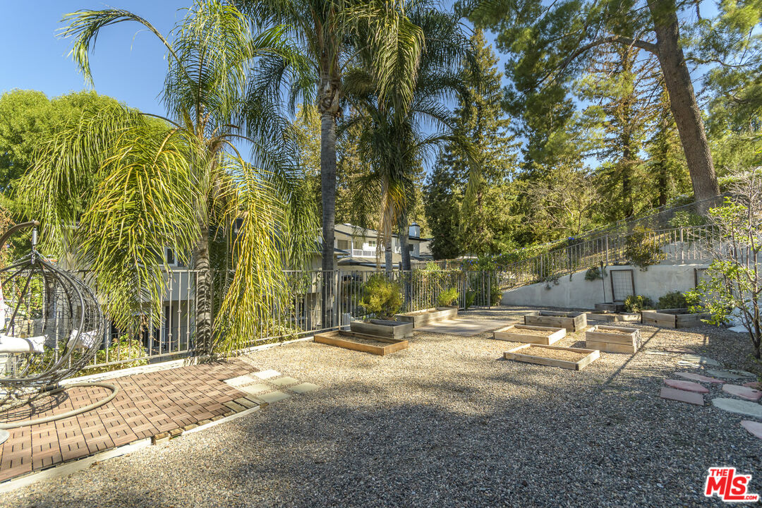 Landscaped yard with raised planter beds, gravel, a brick patio, and tall palms.