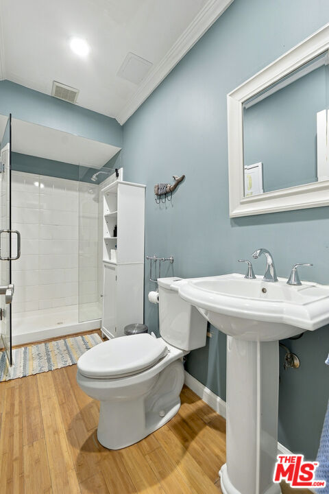 Bathroom with blue-gray walls, a pedestal sink, toilet, and glass-enclosed tiled shower.