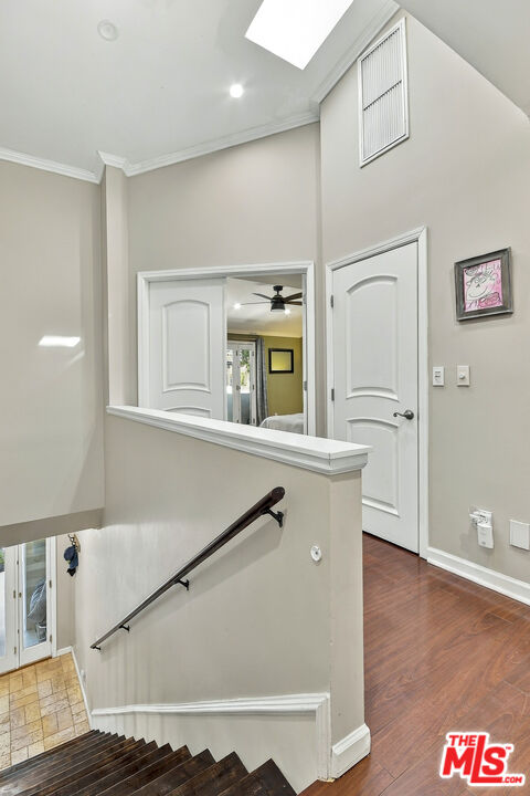 Stair landing with dark wood steps, a black handrail, and a skylight.