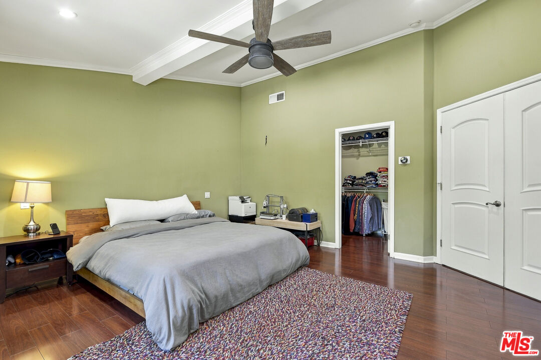 Furnished bedroom with sage-green walls, a large bed, patterned rug, and open closet.