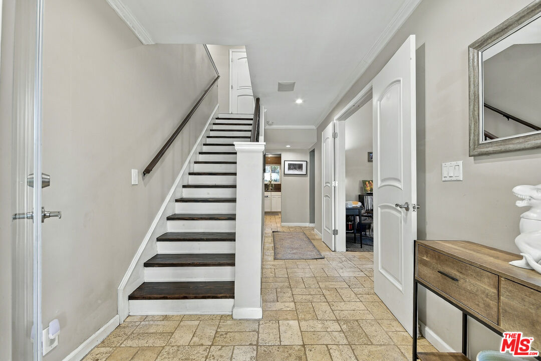 Entry hall with a dark-tread staircase, tiled floor, and console table.