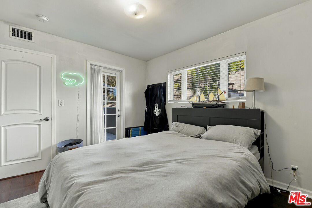 Bedroom with a large bed, model boats on the headboard, and a glowing crocodile-shaped wall light.