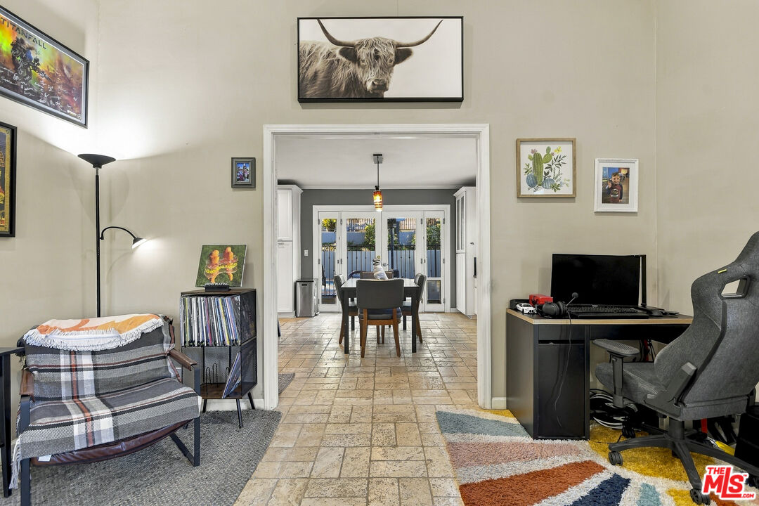 Furnished living room and home office open to a dining room with glass doors.