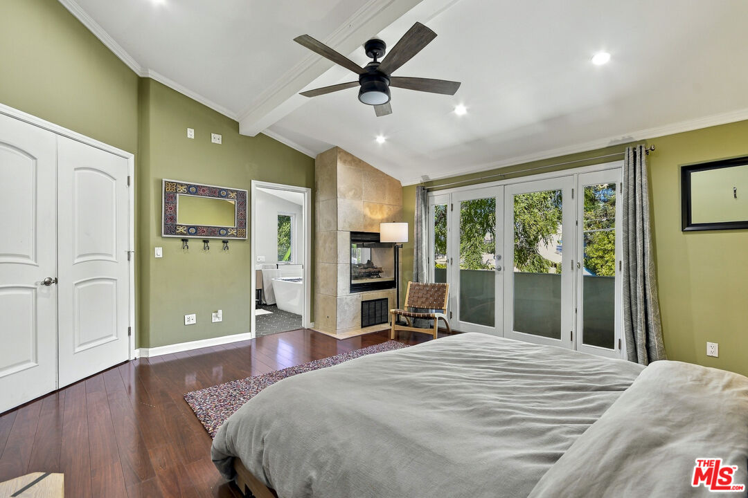 Bedroom with a stone fireplace and glass doors opening to a balcony.