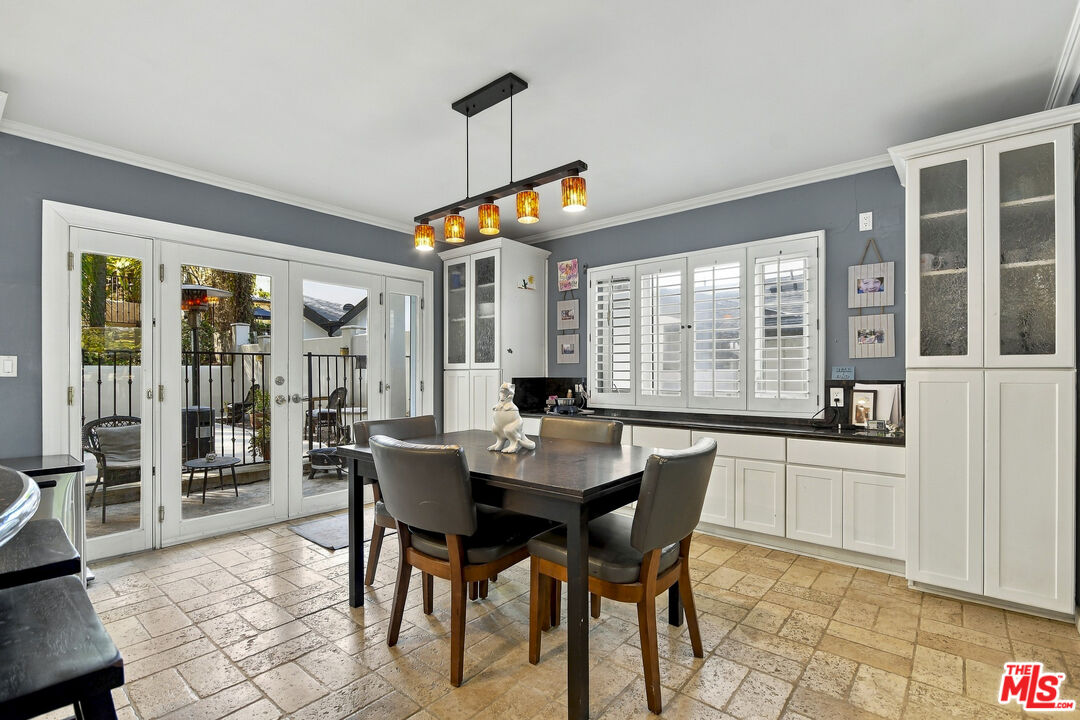 Dining area with white built-in cabinetry, shuttered windows, and French doors opening to a patio.