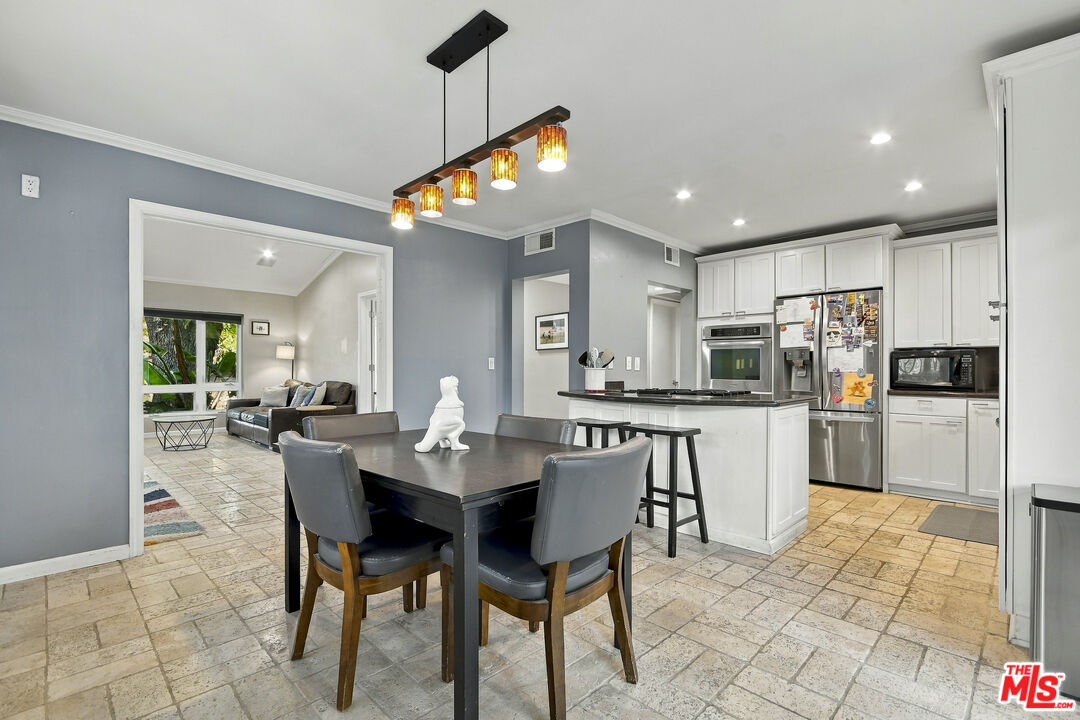 Dining room with a dark table and gray chairs beside an open kitchen with a white island.