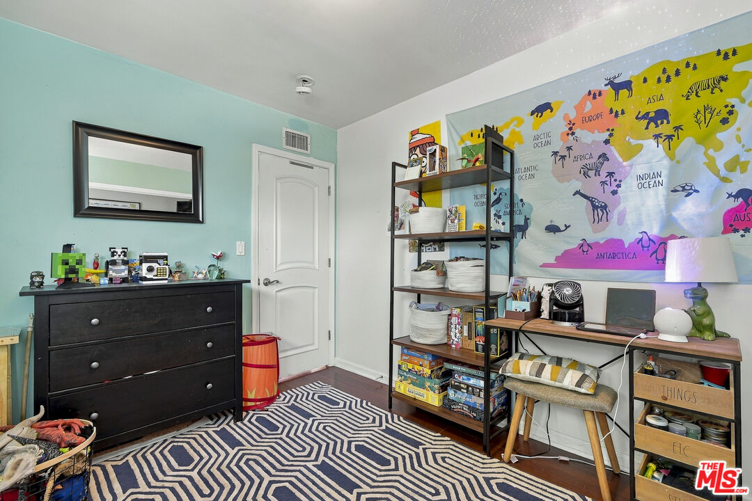 Furnished child’s room with a colorful world map mural, toy-filled shelves, and a geometric rug.