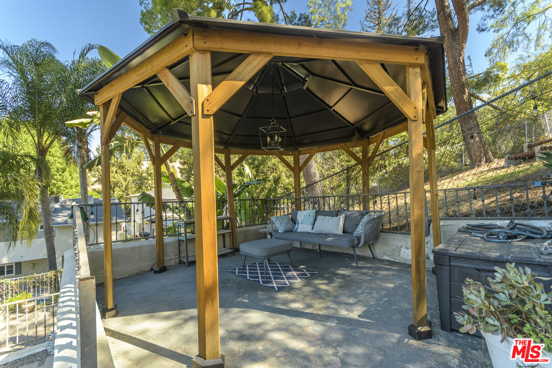 Patio with a timber gazebo, outdoor sofa, and hot tub.