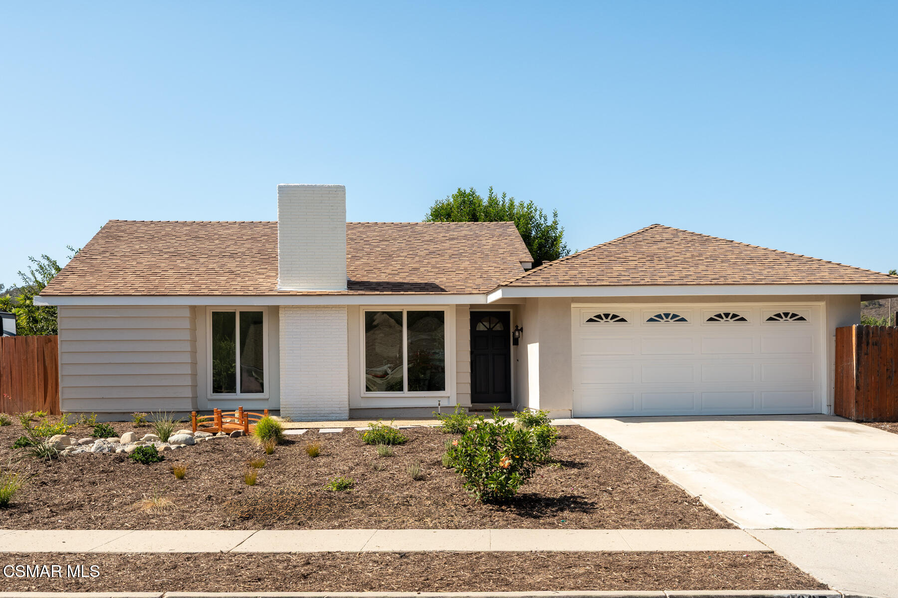 Single-story Thousand Oaks home with a white brick chimney, two-car garage, and drought-tolerant landscaping.