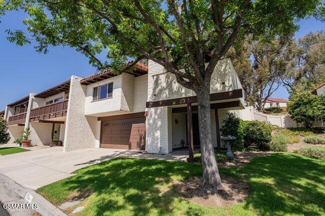 Two-story home with a large shade tree in the front yard and a broad driveway.
