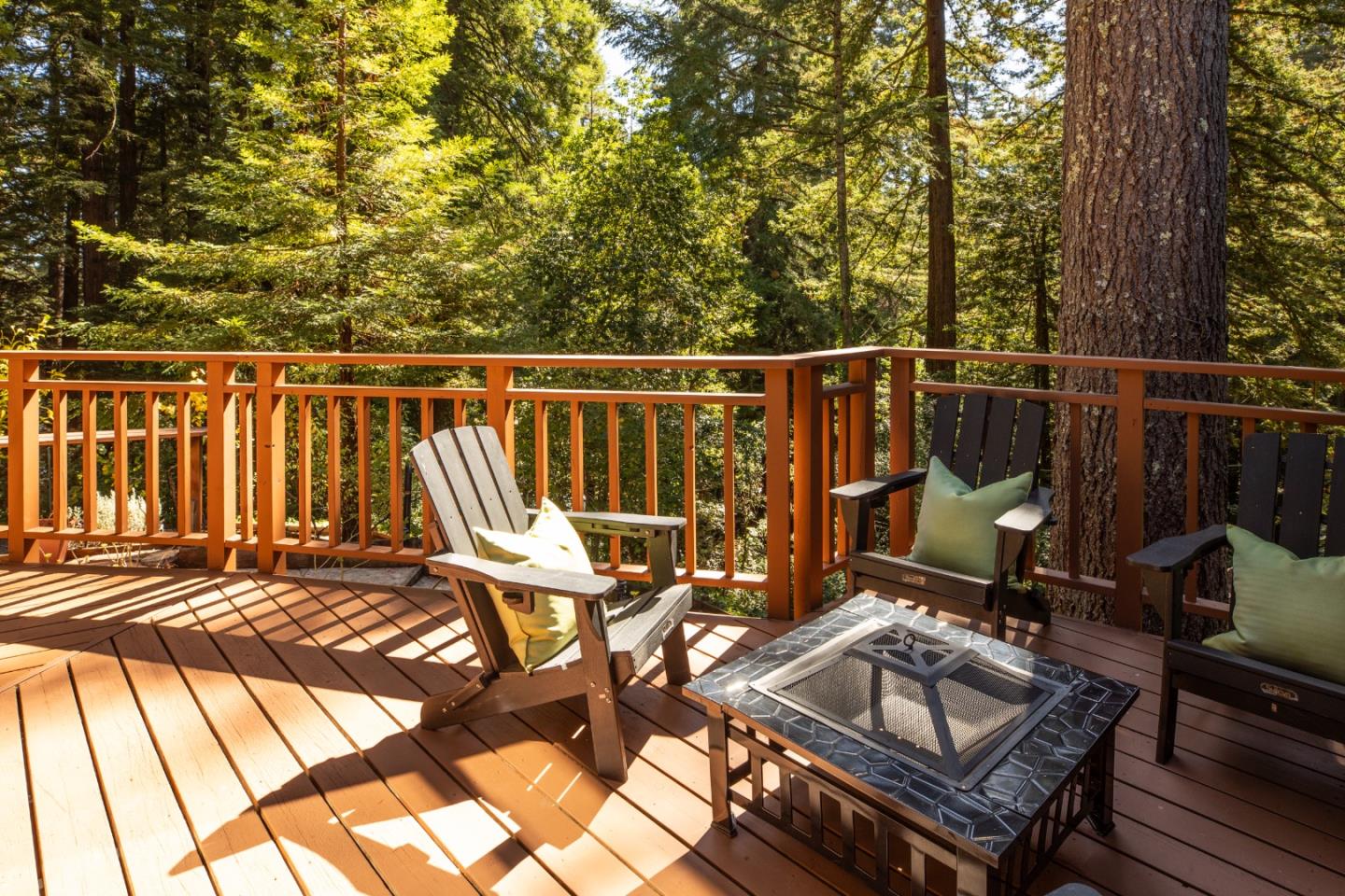 Wooded deck with Adirondack chairs and a tiled fire-pit table.