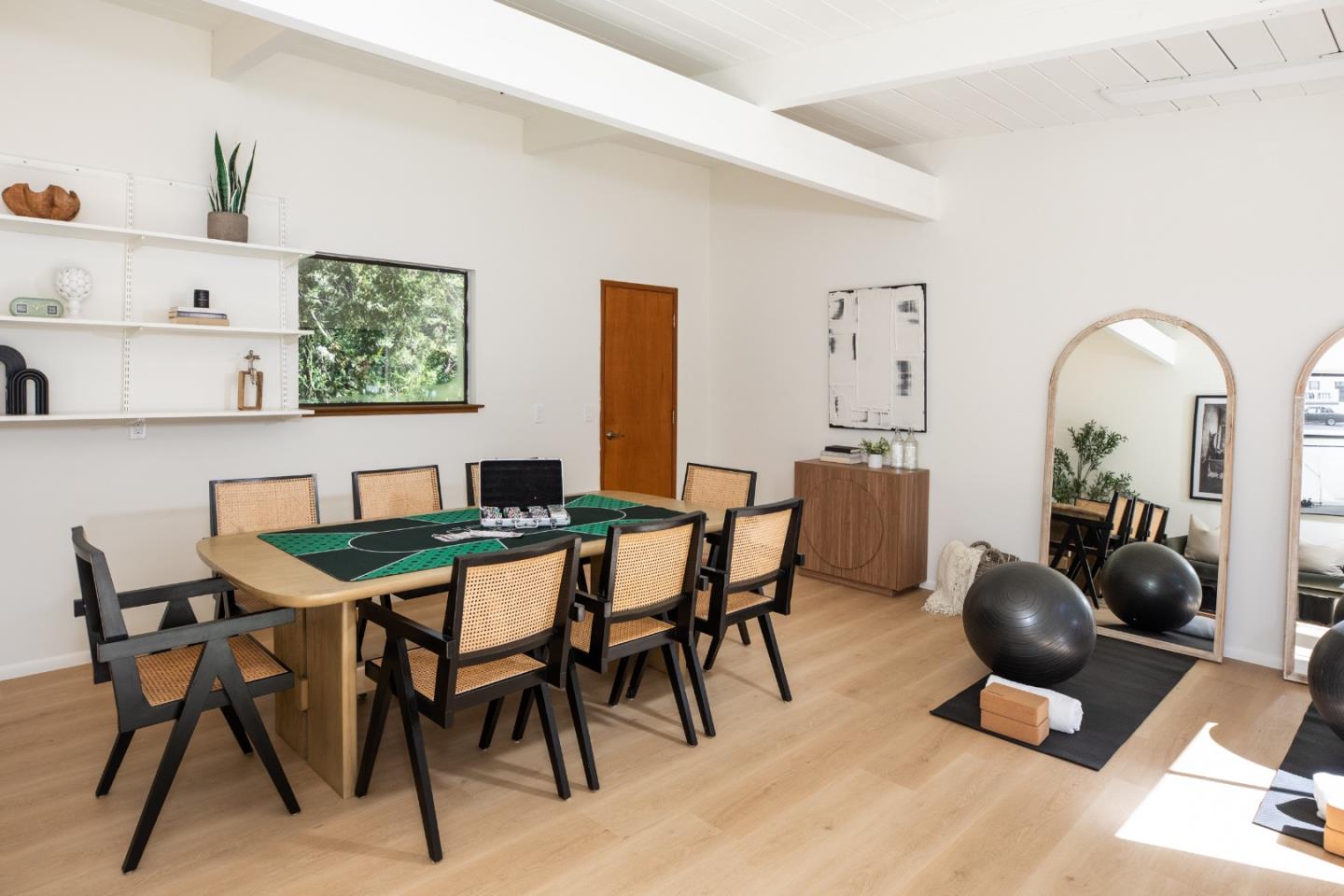 Dining and recreation room with a game table, cane chairs, vaulted ceiling, and arched mirrors.
