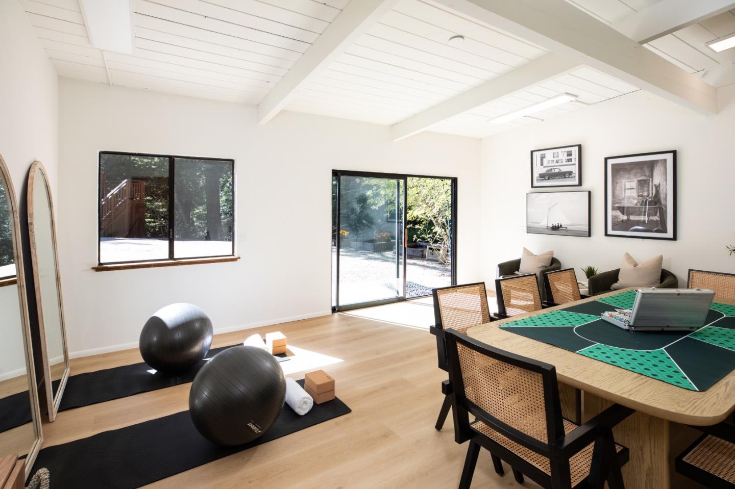 Multipurpose room with exercise mats and stability balls beside a game table and sliding glass doors.