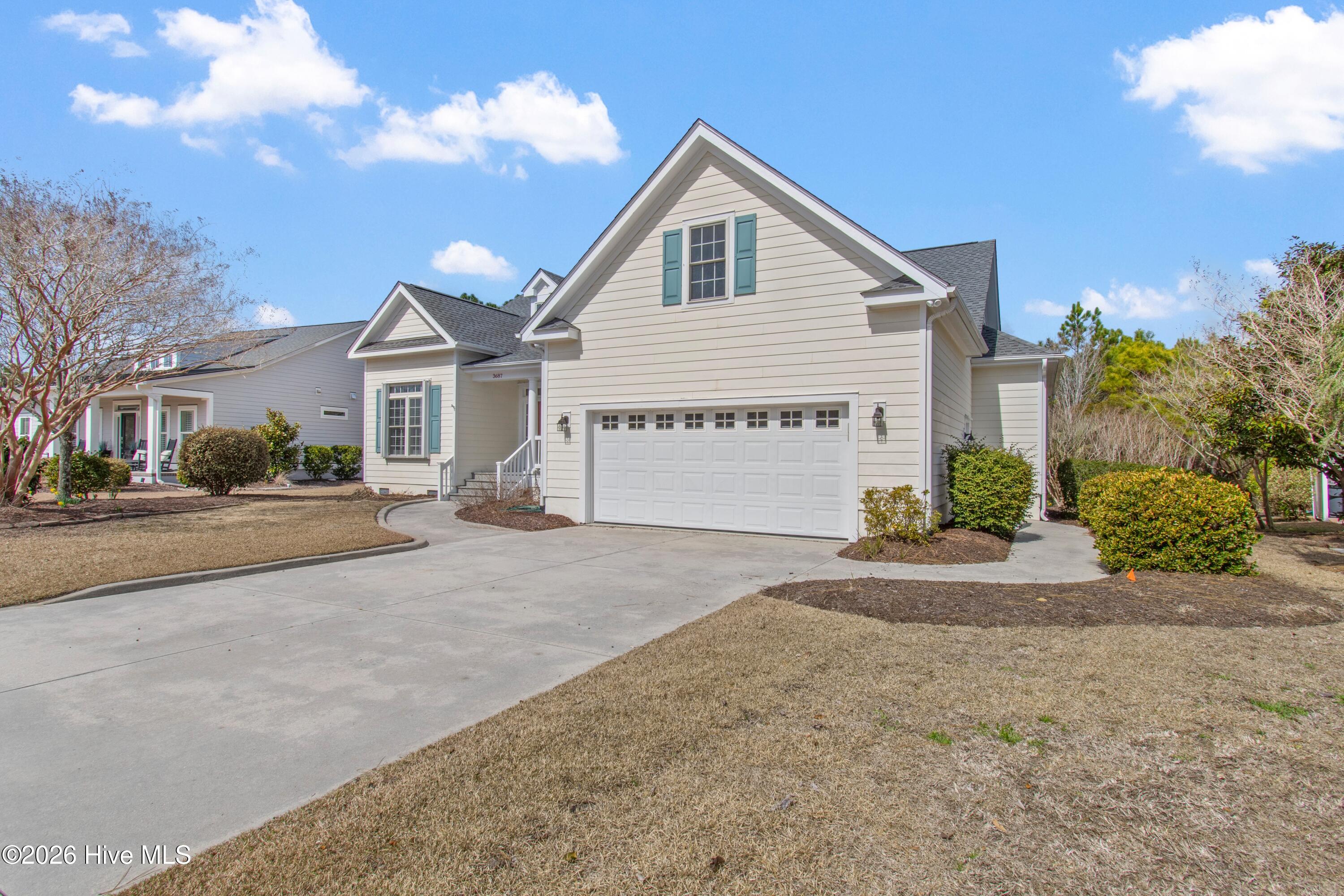 Two-story gabled home with blue-green shutters, double garage, and wide concrete driveway.