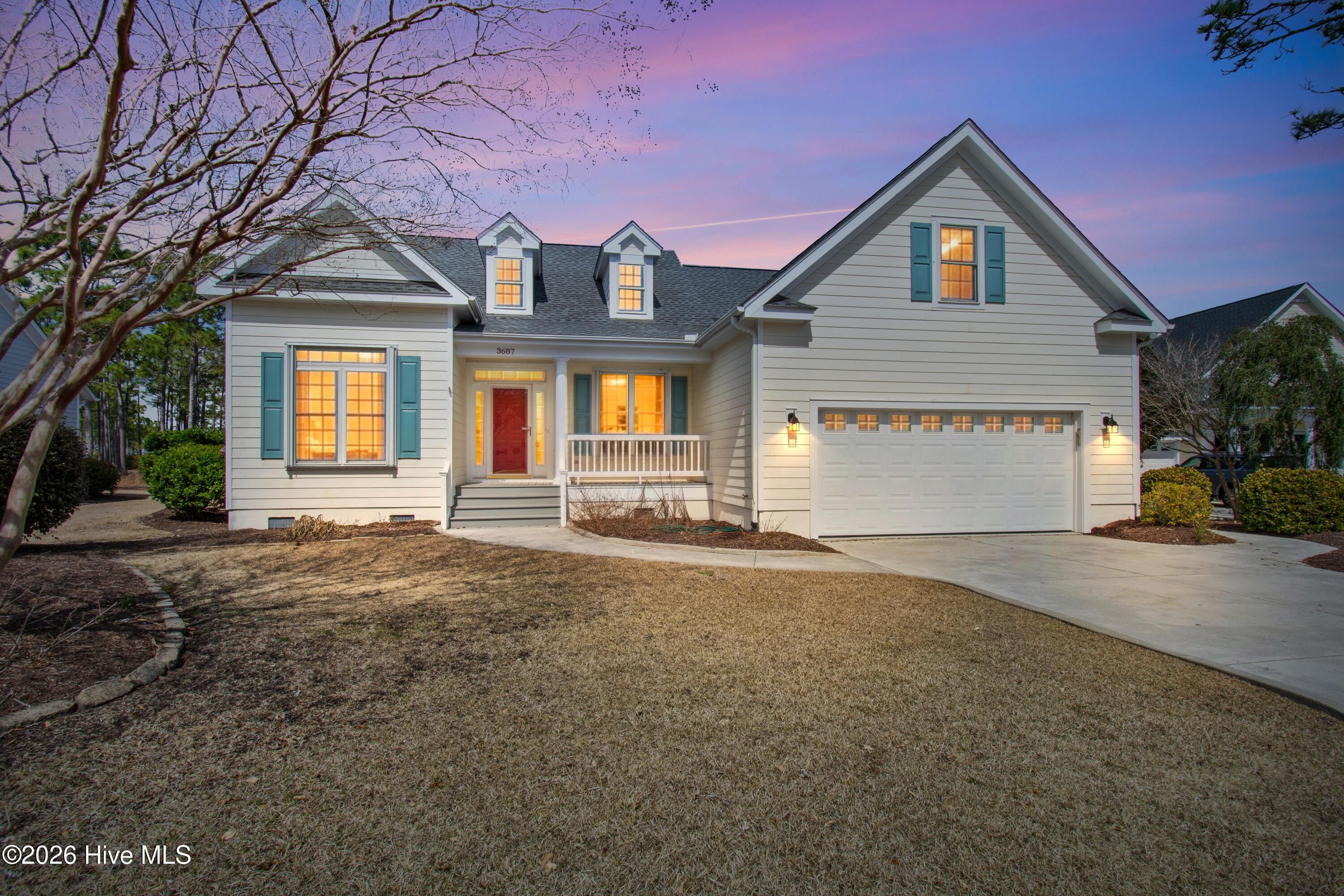 Home exterior with teal shutters, a red front door, and warmly lit windows at dusk.
