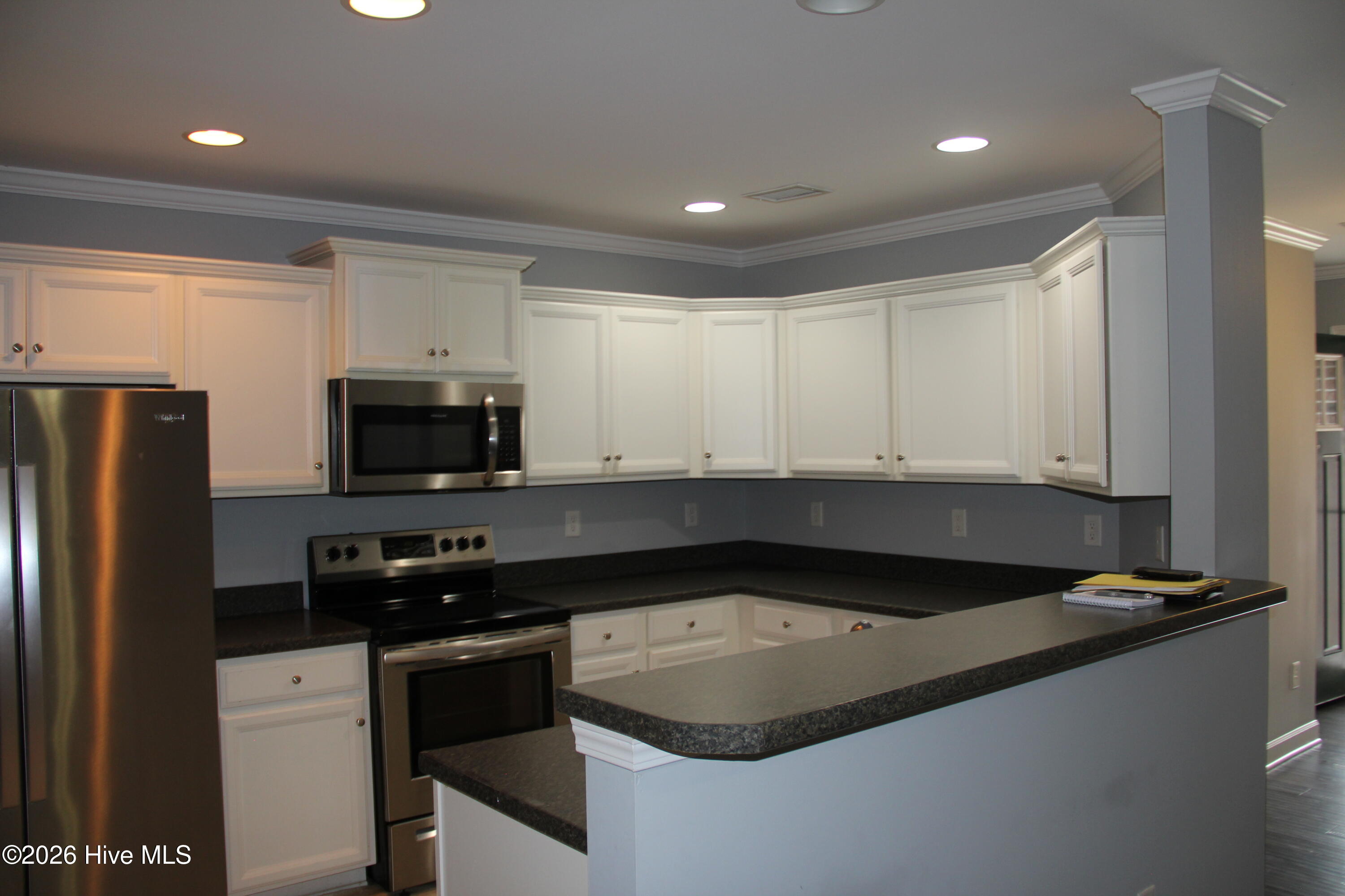 Kitchen with white cabinets, dark granite counters, breakfast bar, and stainless steel appliances.