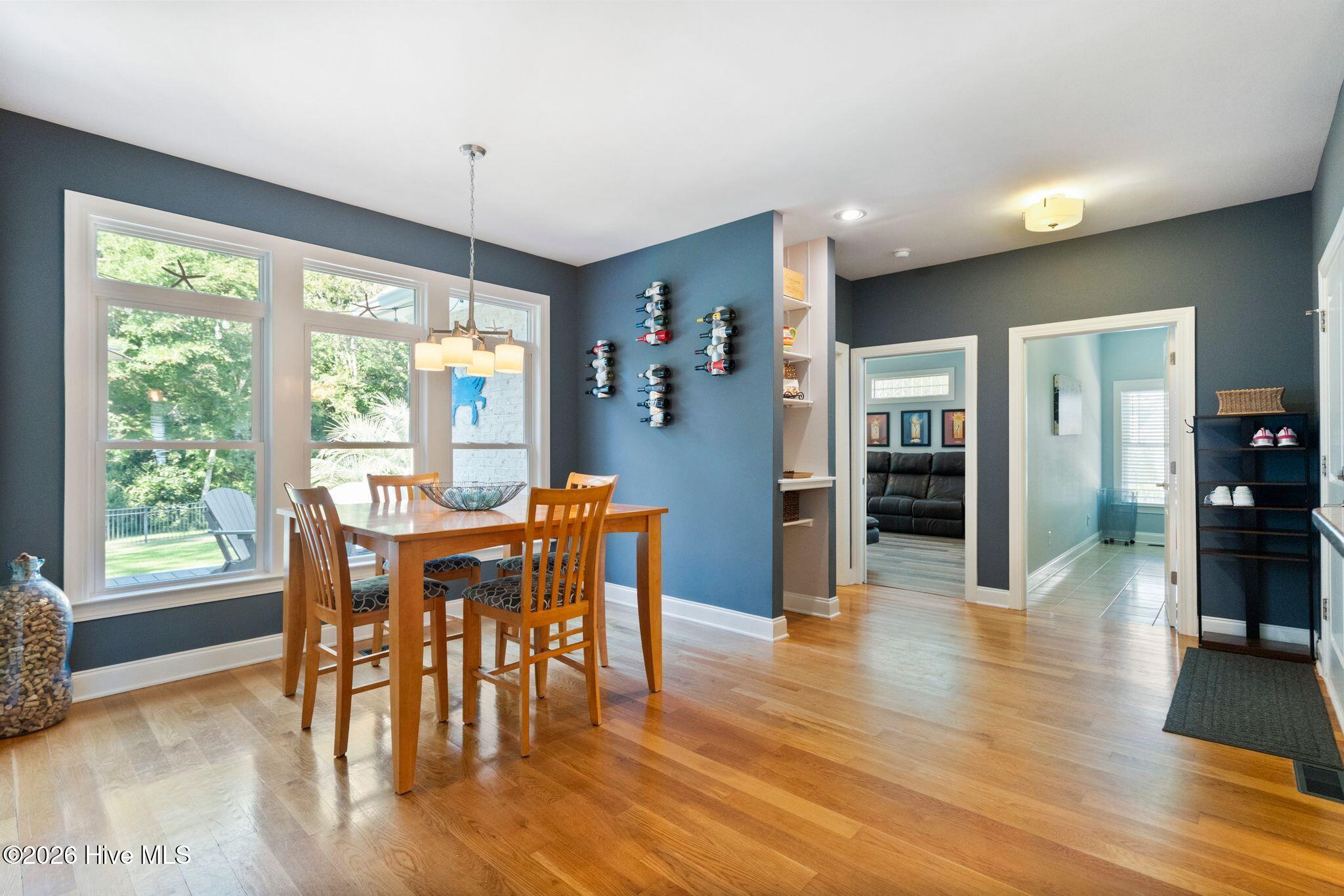 Dining area with a wooden table, large yard-facing windows, and blue walls with wine racks.