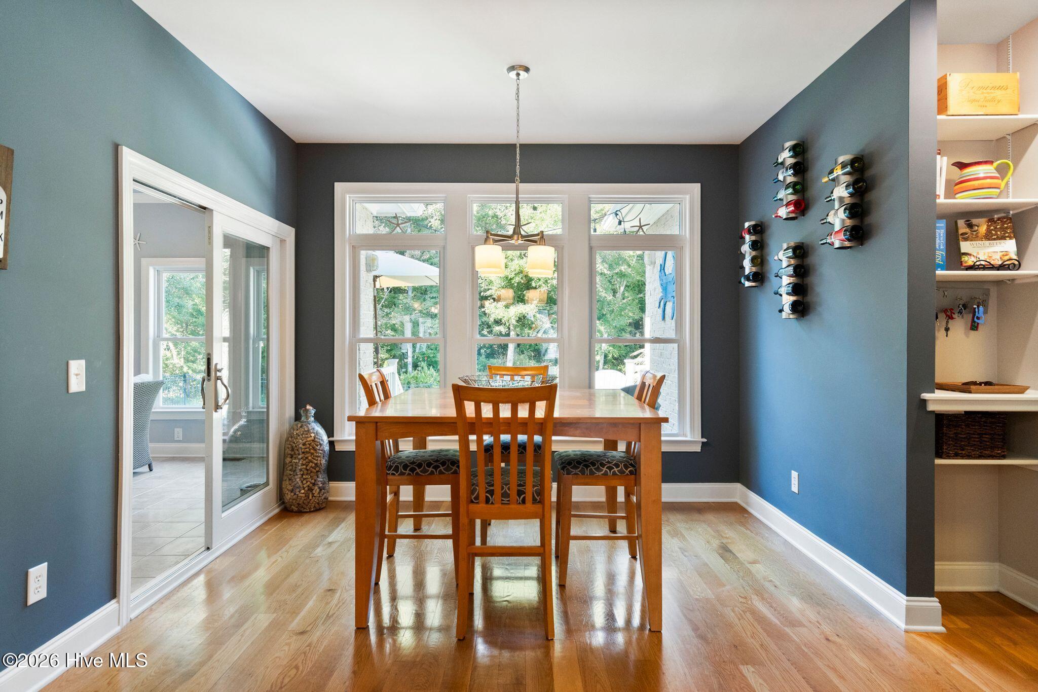 Dining room with a wooden table, large windows, and wall-mounted wine racks.