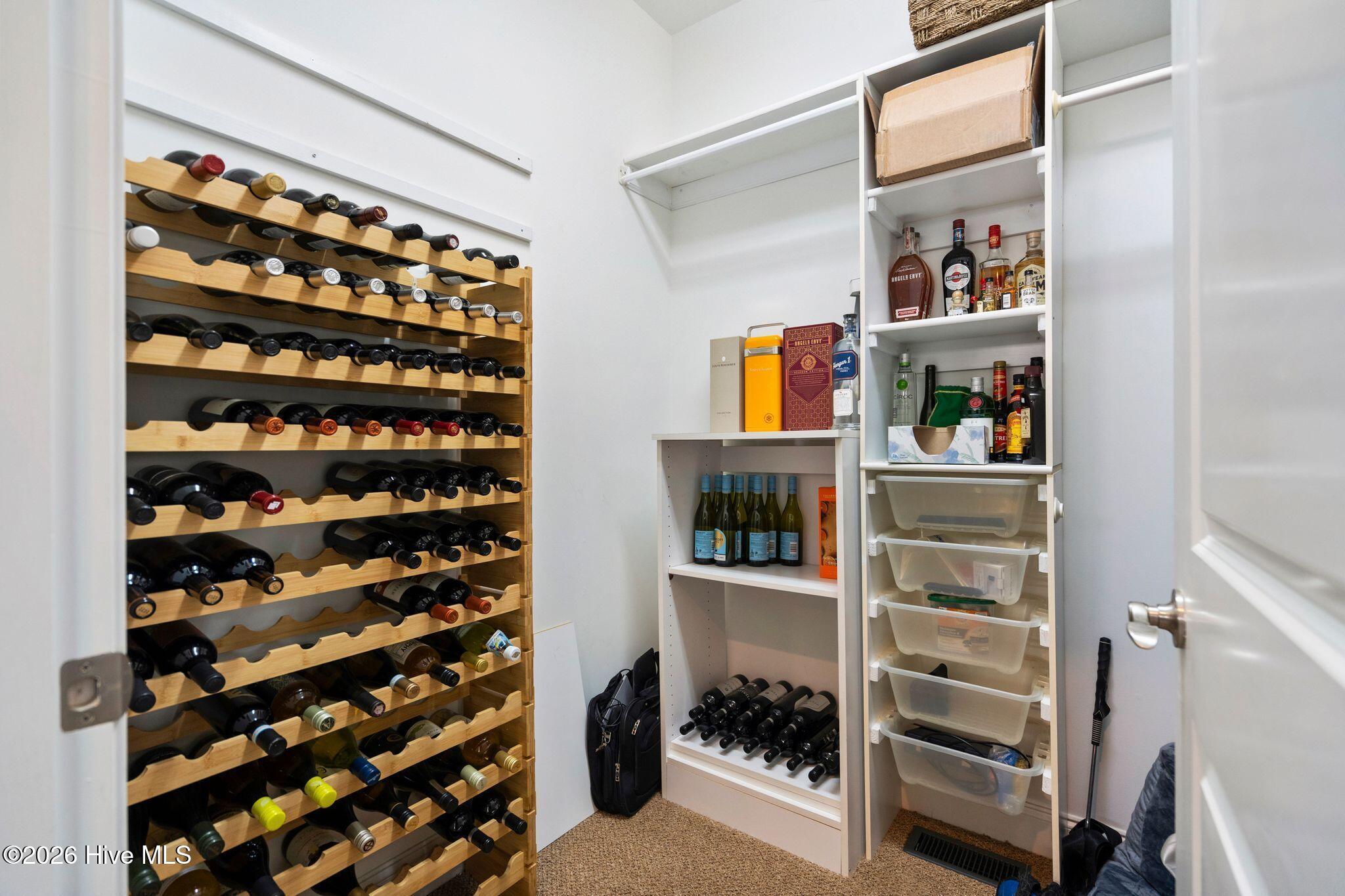 Wine storage room with a large wooden bottle rack and white shelving.