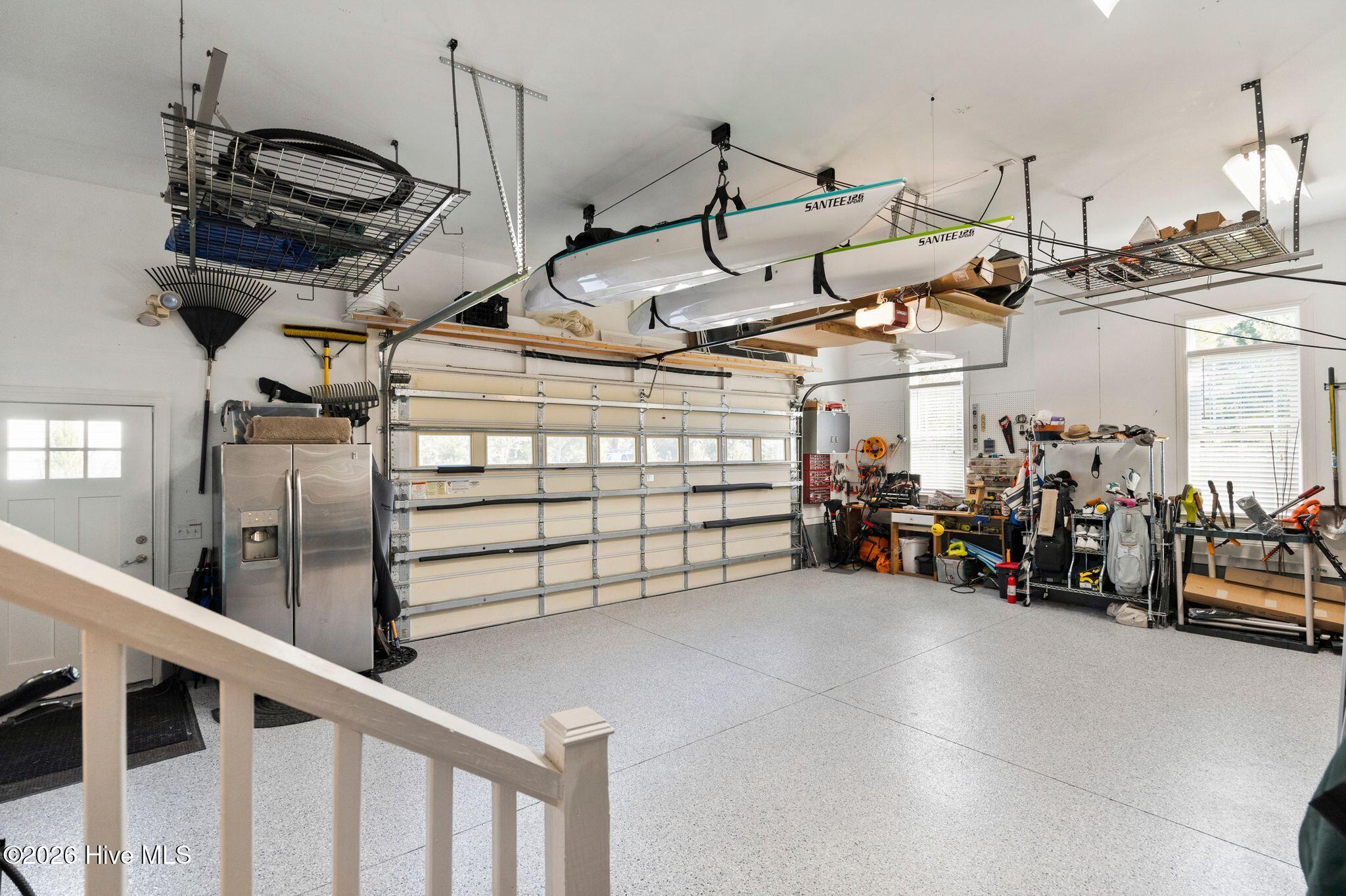 Garage with two kayaks suspended overhead and a workbench along the wall.