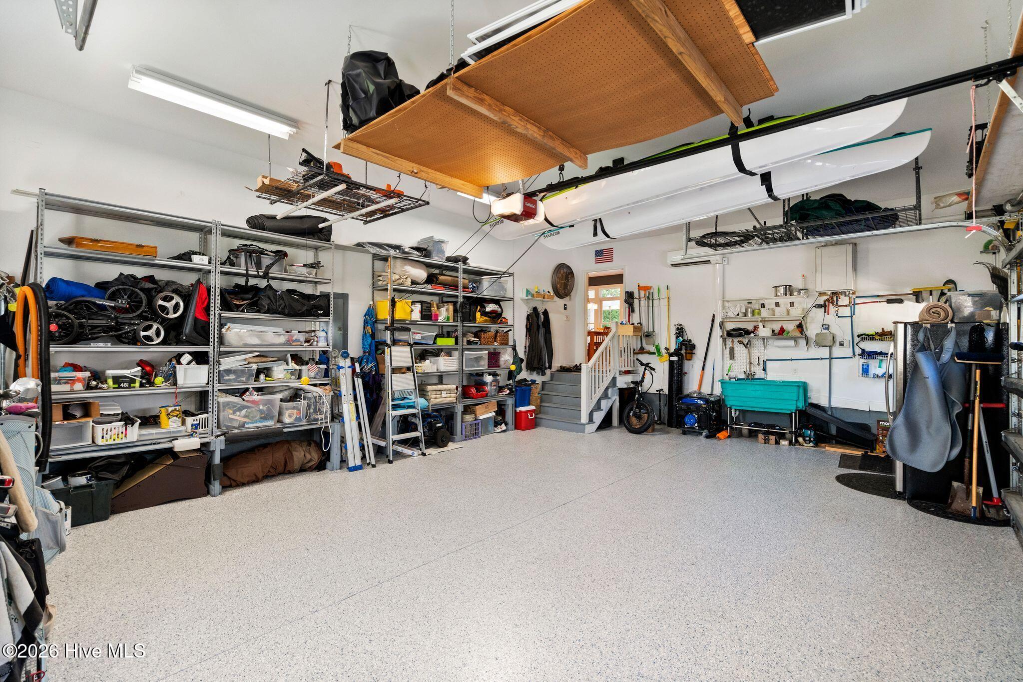 Spacious garage with organized storage shelves, overhead kayaks, and a light speckled floor.