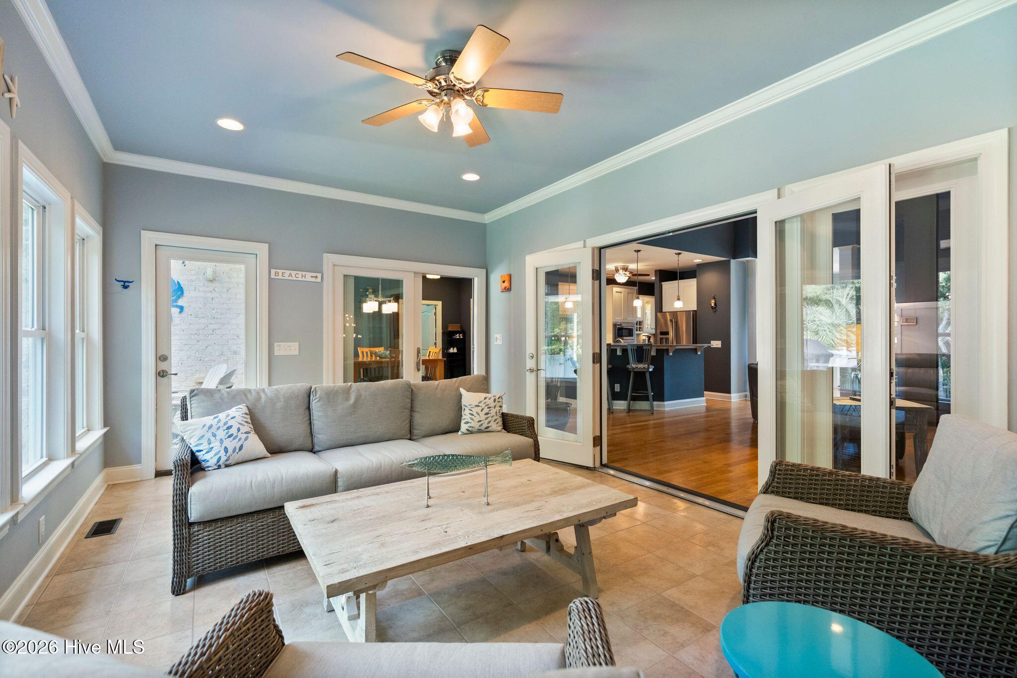 Furnished sunroom with wicker seating and folding glass doors opening to the kitchen.