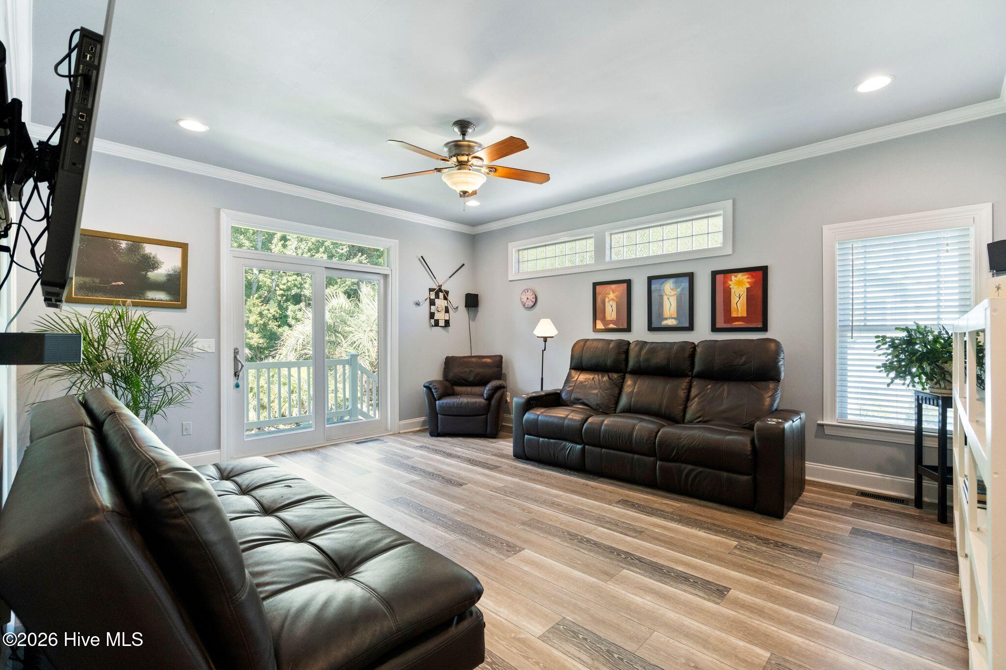 Living room with leather reclining sofas, wood-look floors, and sliding doors opening to a deck.