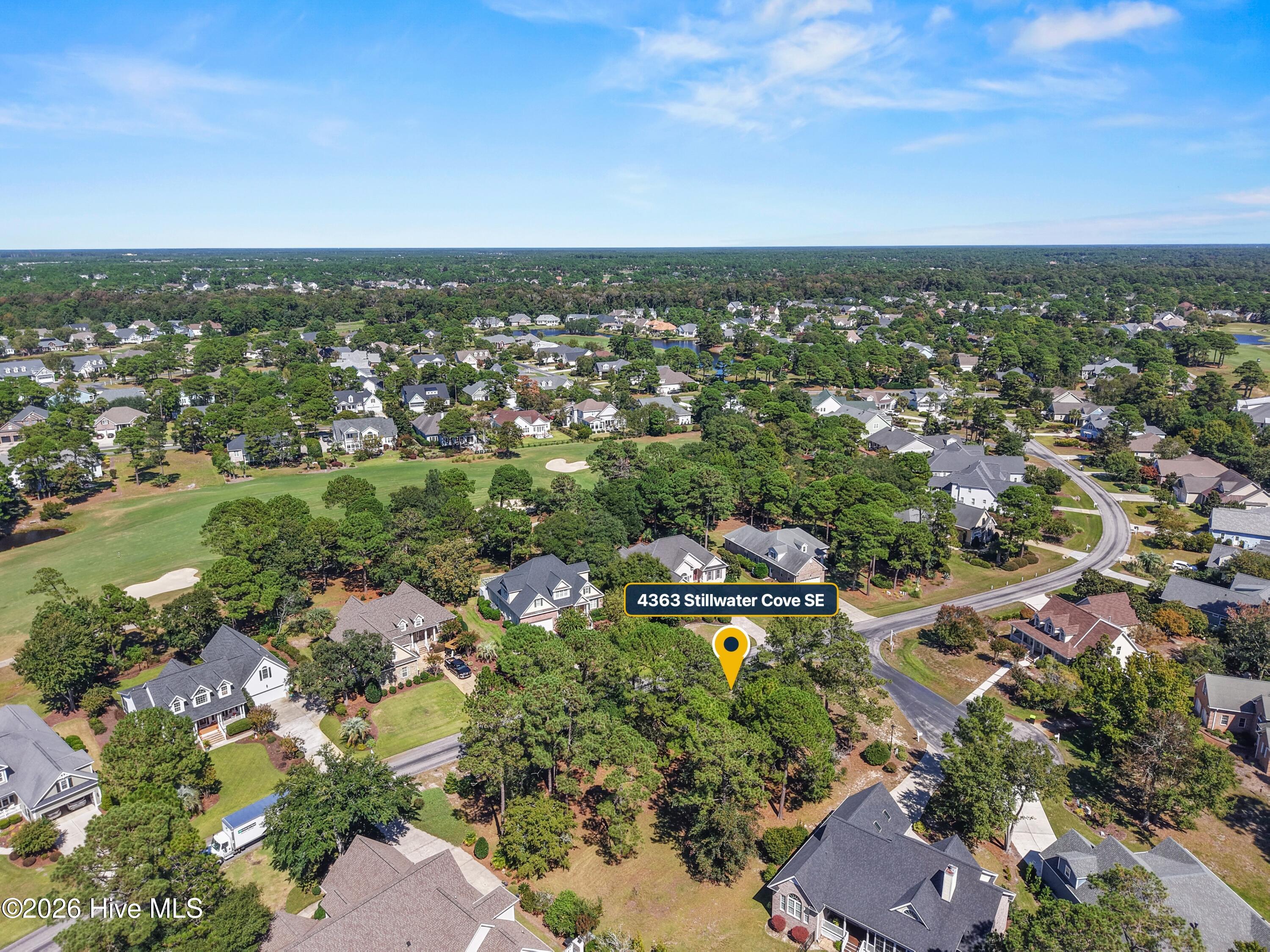 Aerial view of 4363 Stillwater Cove SE among homes, trees, and a nearby golf green.
