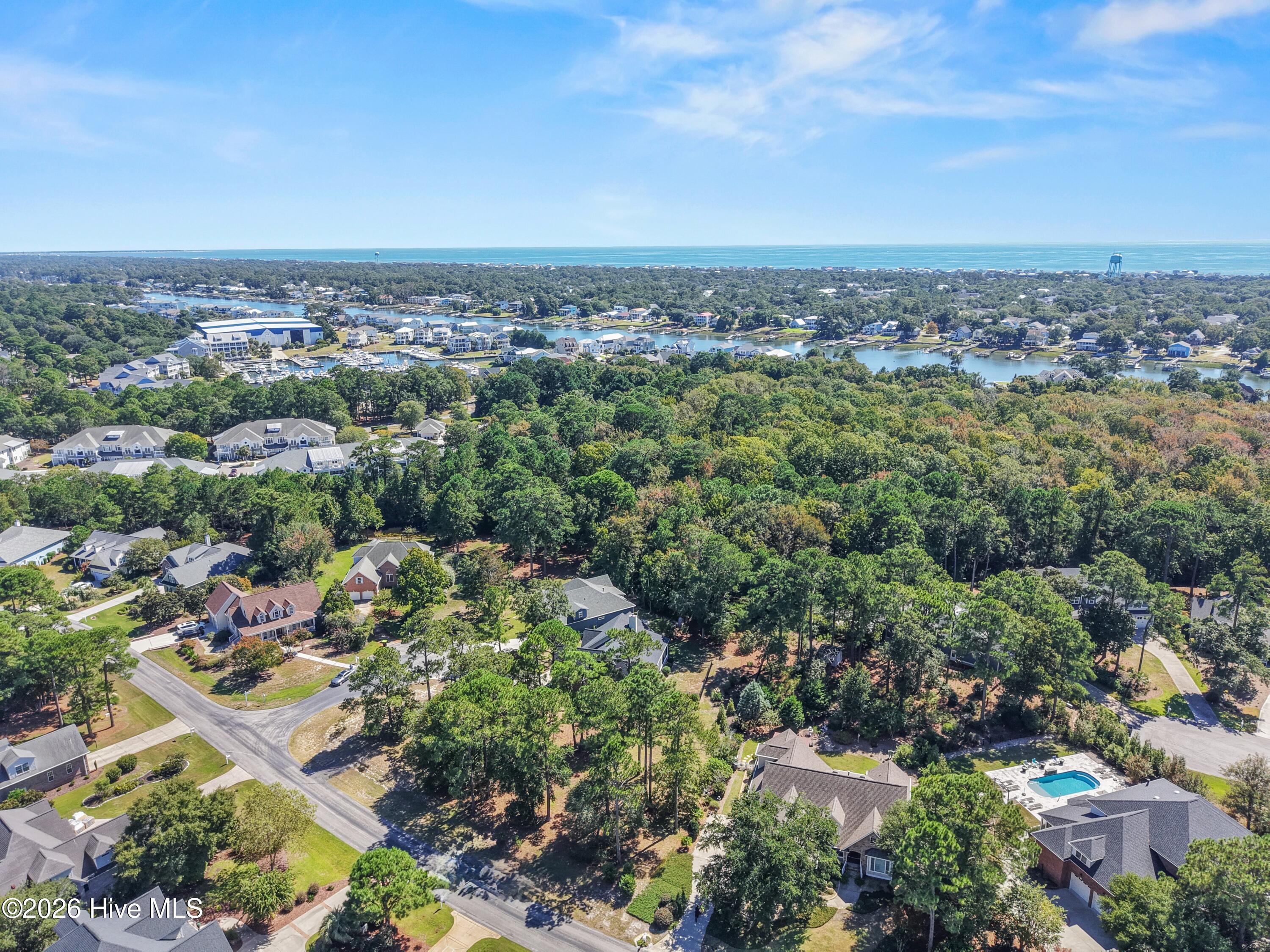 Aerial view of a wooded neighborhood, marina, coastal waterways, and ocean horizon.