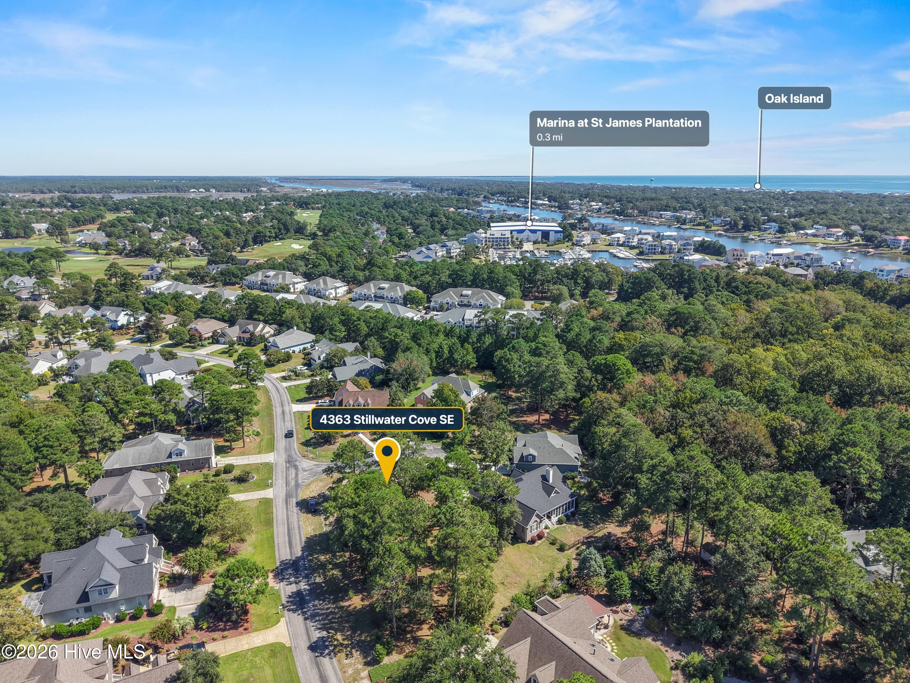 Aerial view of 4363 Stillwater Cove SE, surrounded by trees near a marina and the coast.