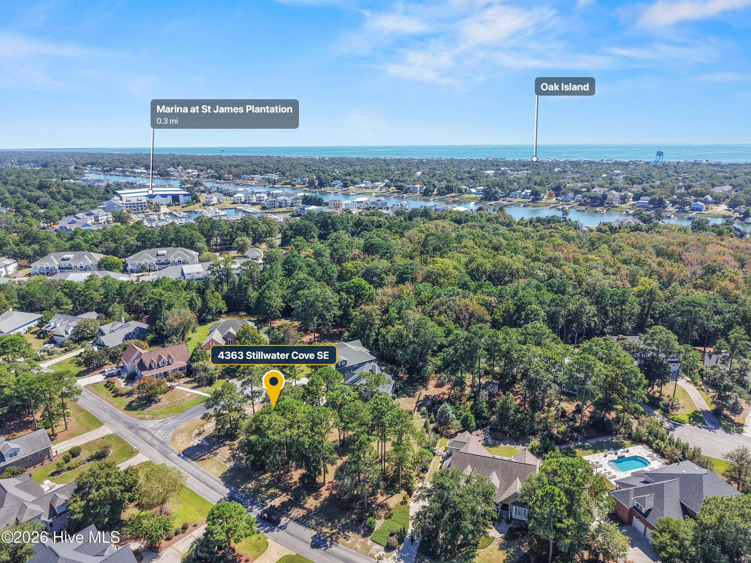 Aerial view of 4363 Stillwater Cove SE, with the marina and ocean visible beyond the wooded neighborhood.