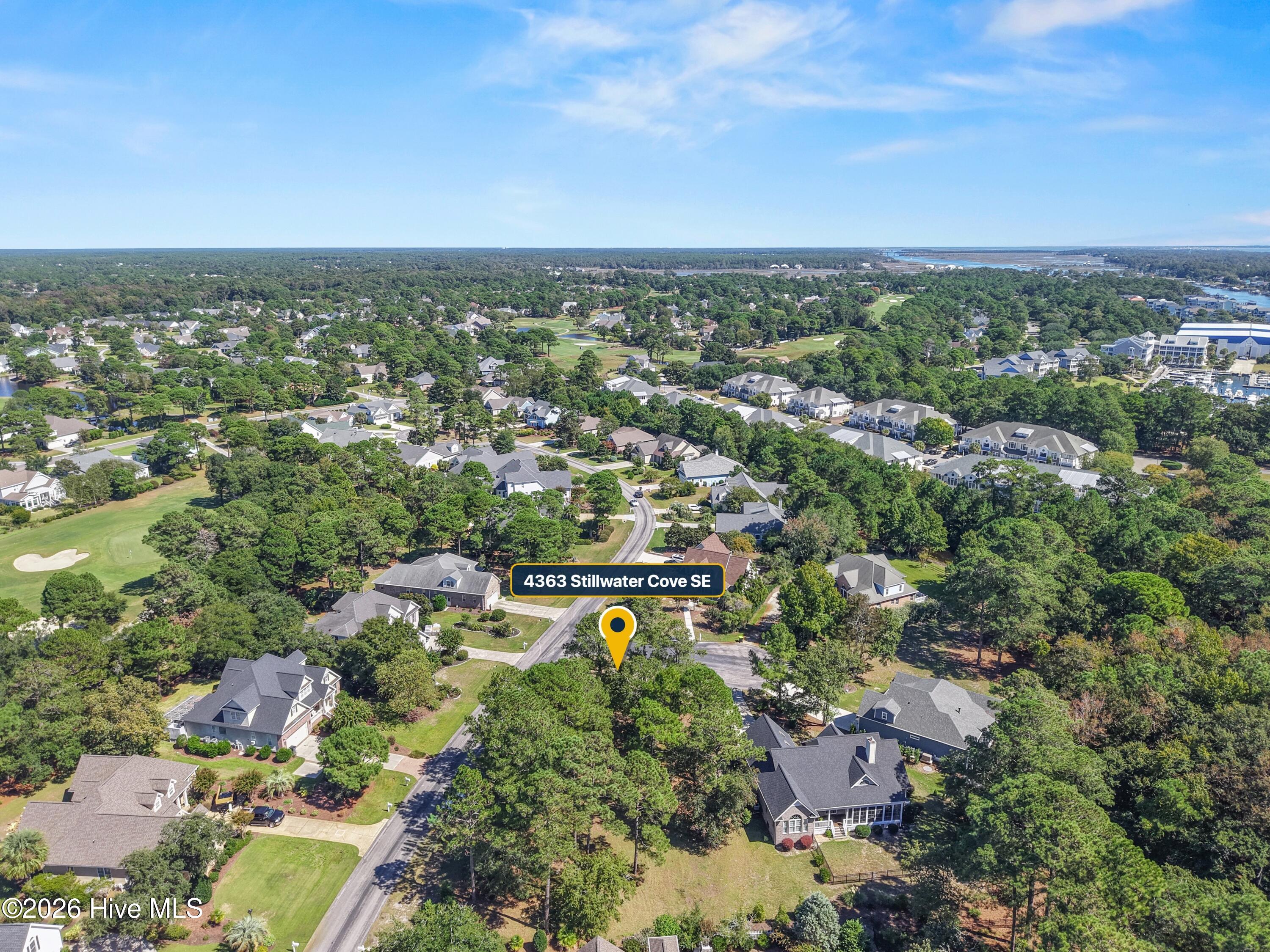 Aerial view of 4363 Stillwater Cove SE’s leafy neighborhood, with a golf course and distant marina.
