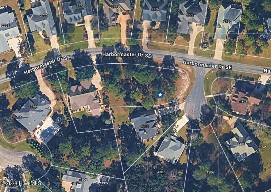 Aerial view of a wooded residential lot marked by a blue star among homes and parcel lines.