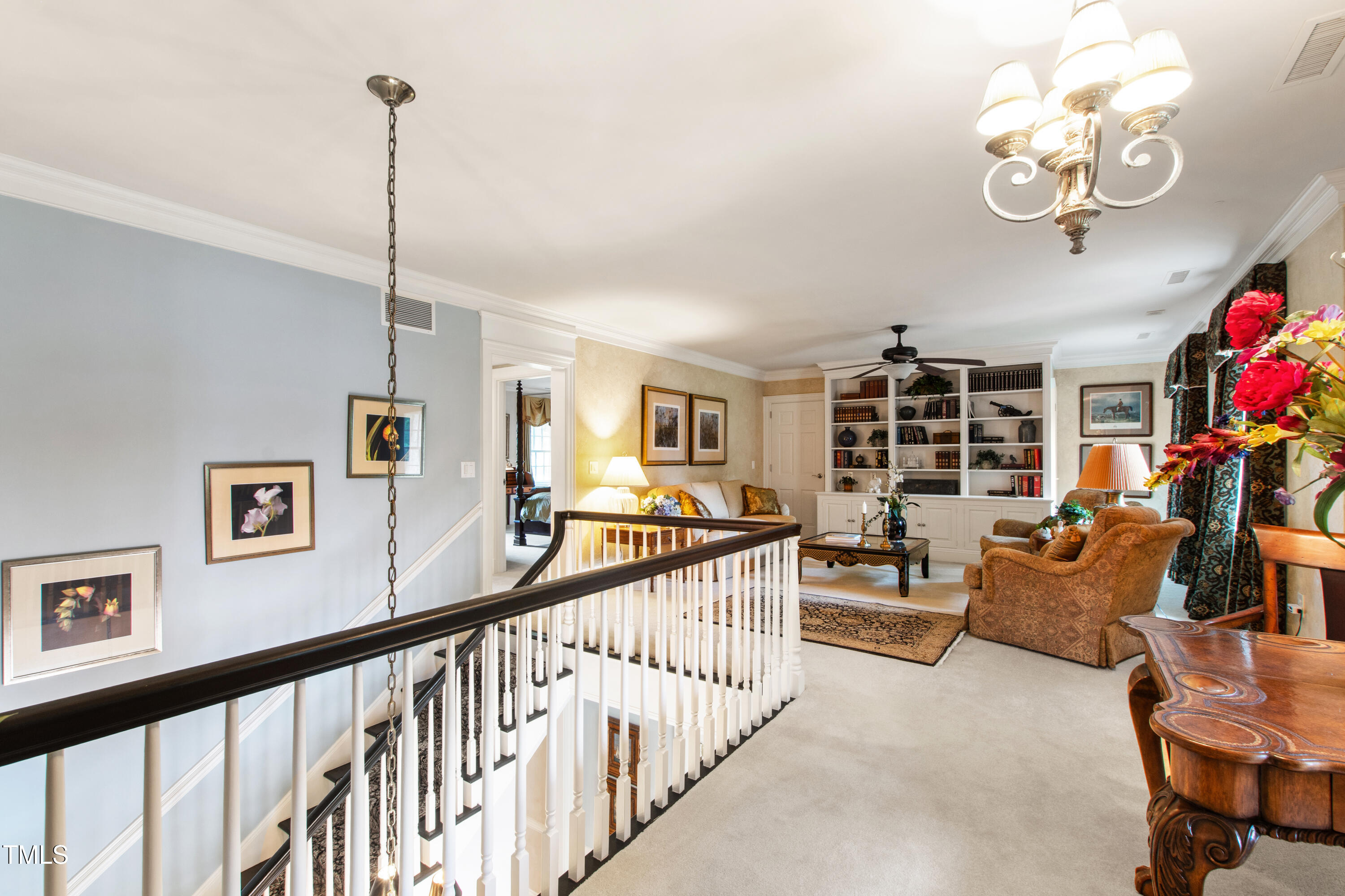 Upstairs sitting area overlooking the staircase, with built-in bookshelves and a dark wood railing.