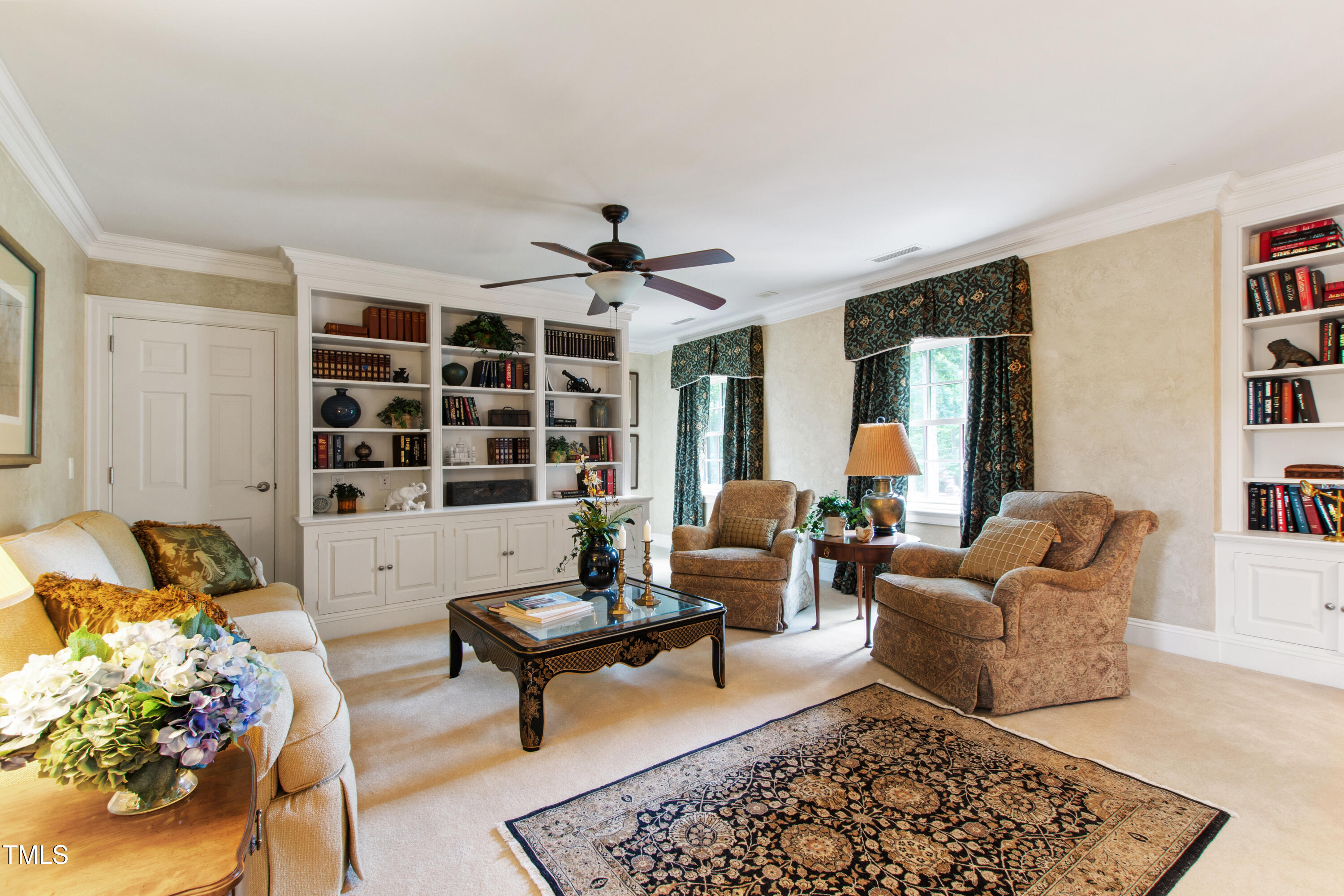 Living room with built-in bookshelves, patterned curtains, and a large decorative rug.