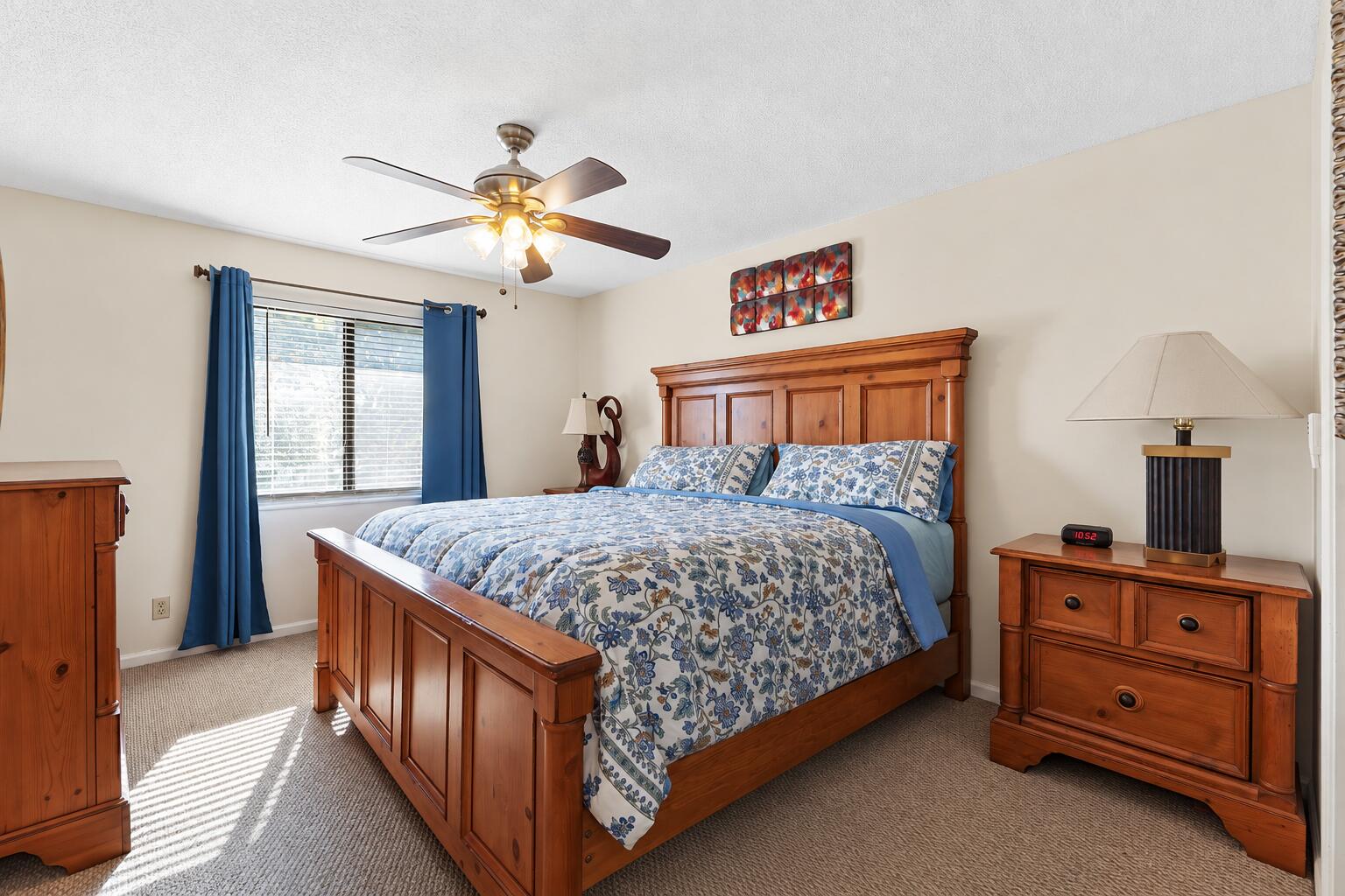 Bedroom with a wooden bed, blue floral bedding, matching dressers, and blue curtains.