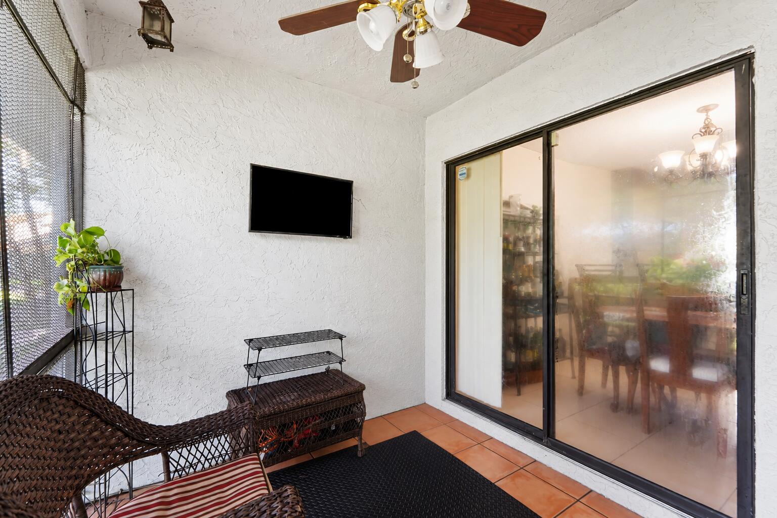 Covered patio with wicker seating, terracotta tile, and sliding glass doors.