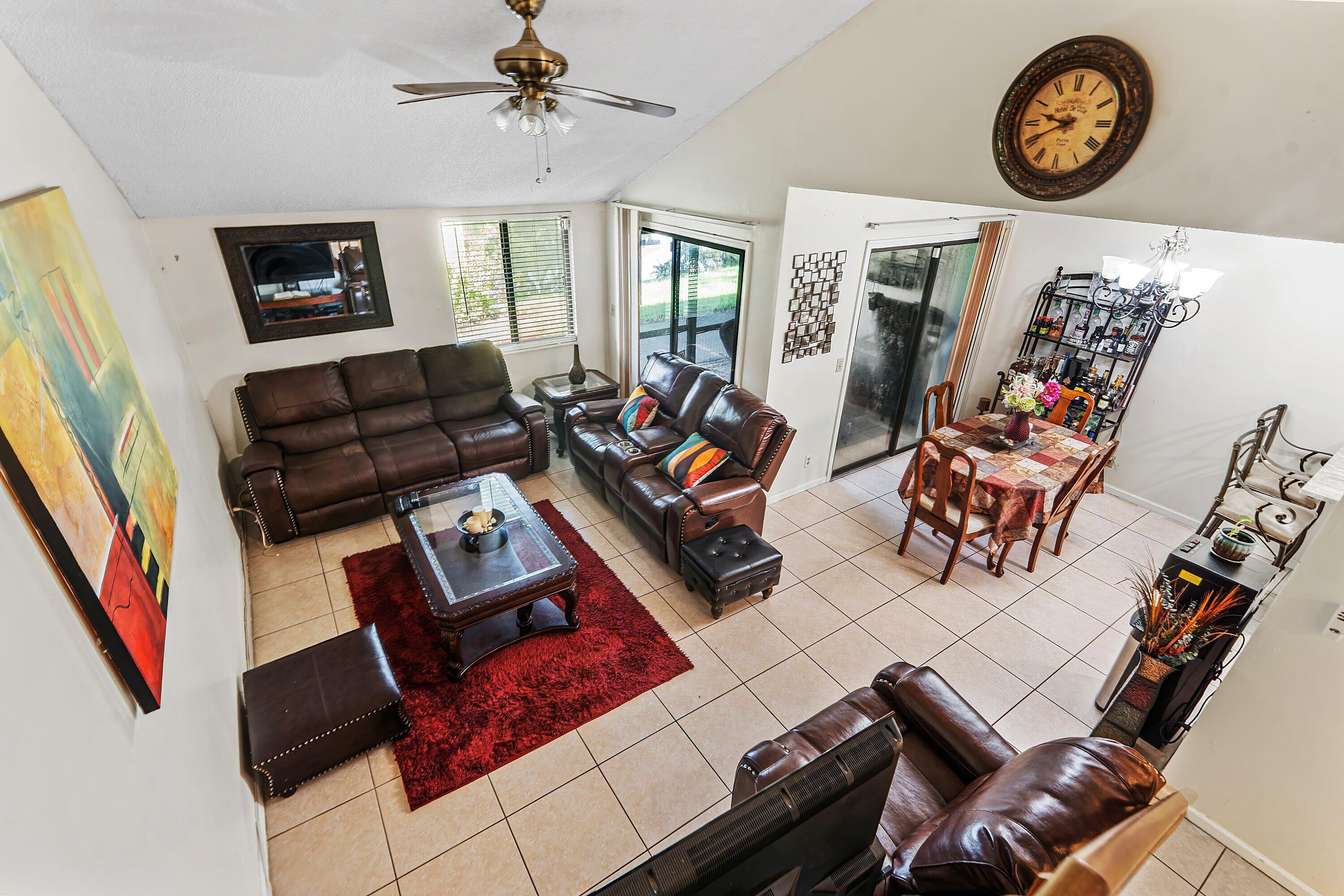 Living room with dark leather seating, a red rug, and an adjoining dining area by sliding glass doors.