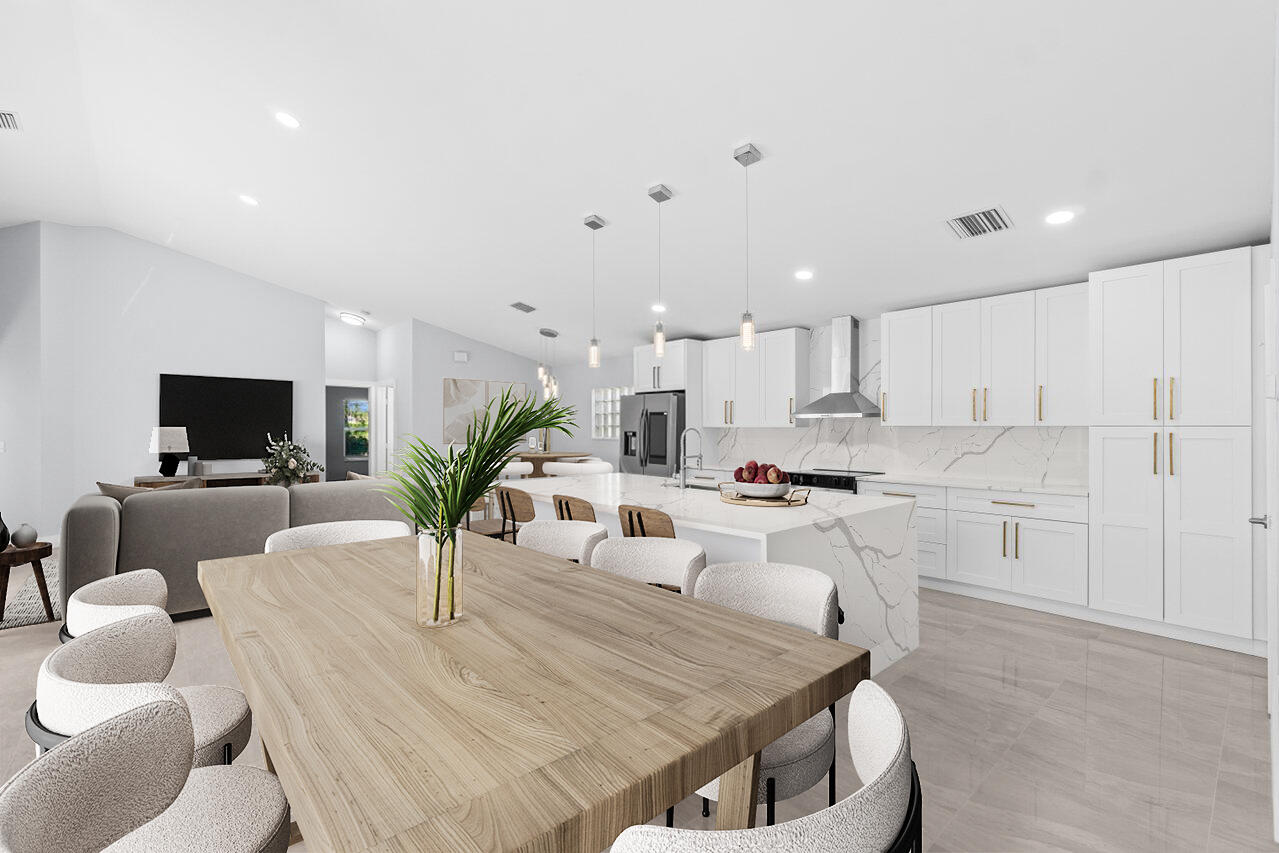 Open-plan kitchen and dining area with white cabinets, a veined stone island, and a large wood table.