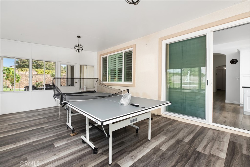 Recreation room with a ping-pong table, gray flooring, and large windows.