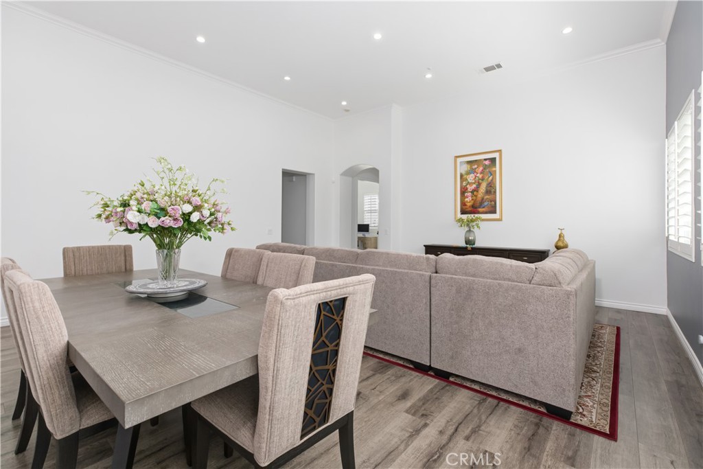 Dining area and living room with a large table, flower centerpiece, and beige sectional sofa.