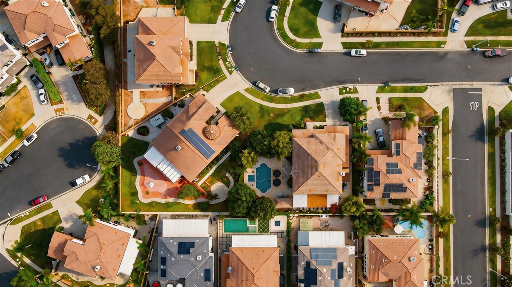 Aerial view of homes on a residential street, with swimming pools and solar panels.