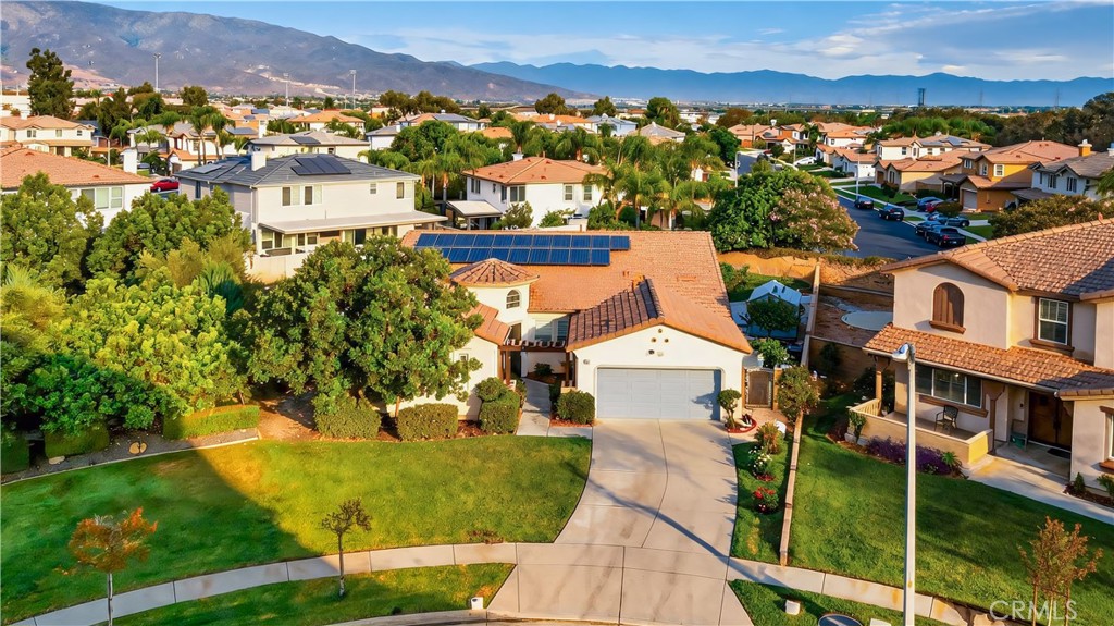 Aerial view of a tile-roofed home with rooftop solar panels and mountain views.