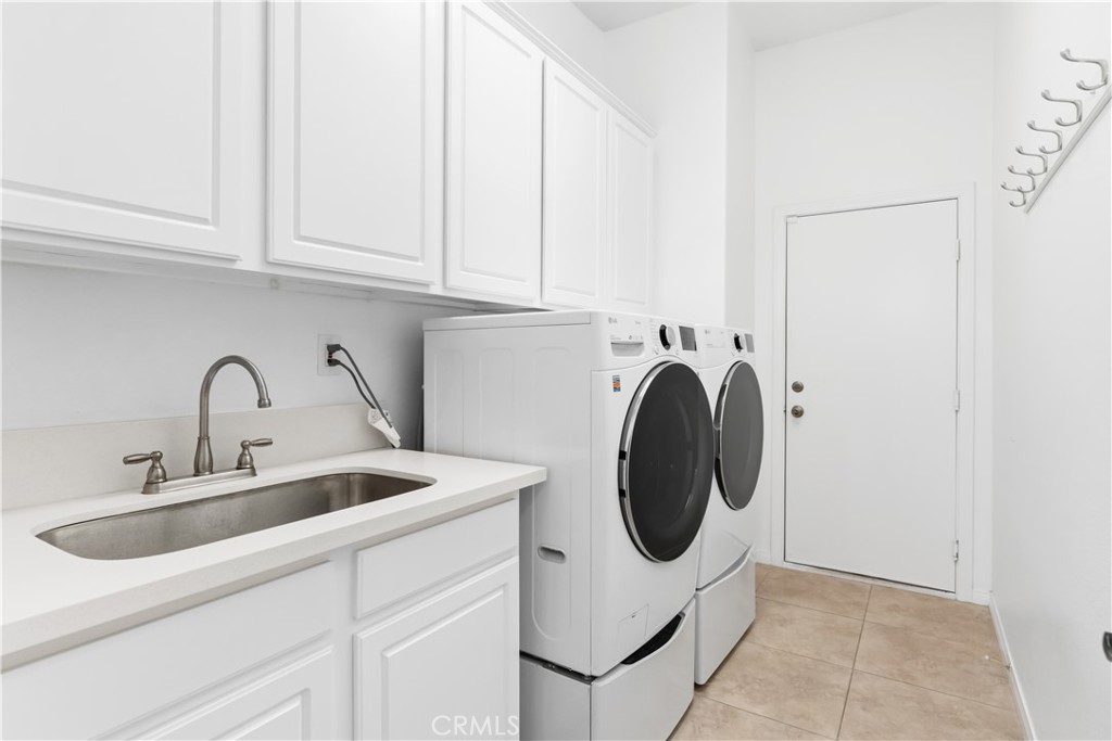 Laundry room with white cabinets, a utility sink, and front-loading washer and dryer.