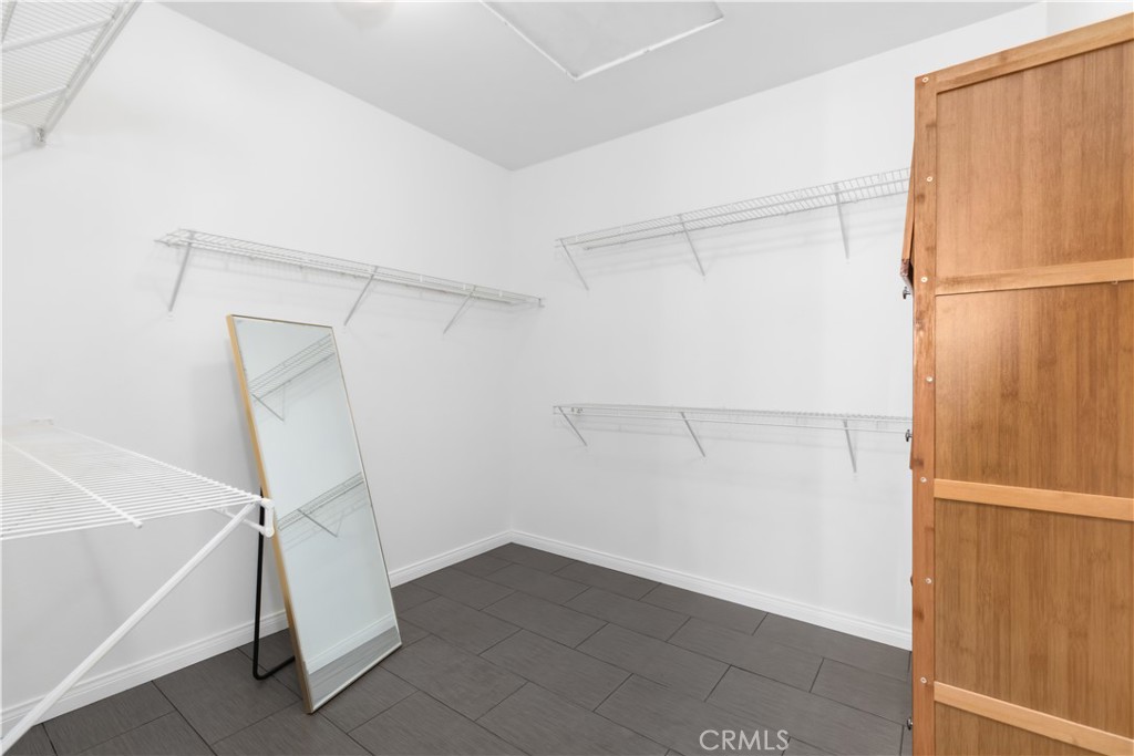 Walk-in closet with wire shelving, a leaning full-length mirror, and gray tile flooring.