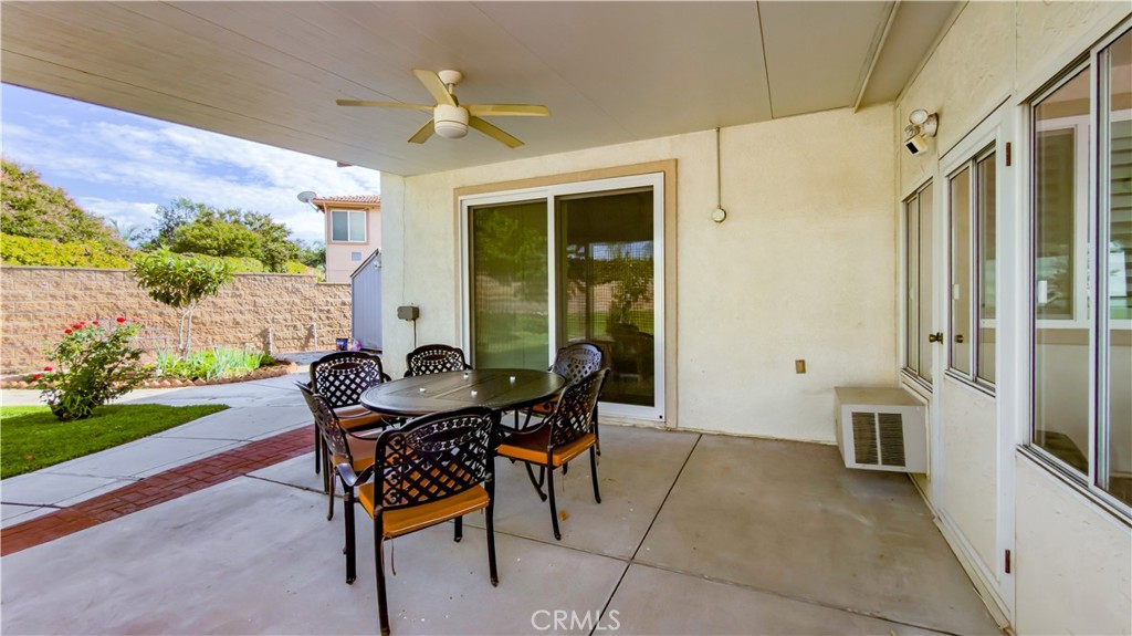 Covered patio with outdoor dining set and ceiling fan, opening onto a landscaped backyard.