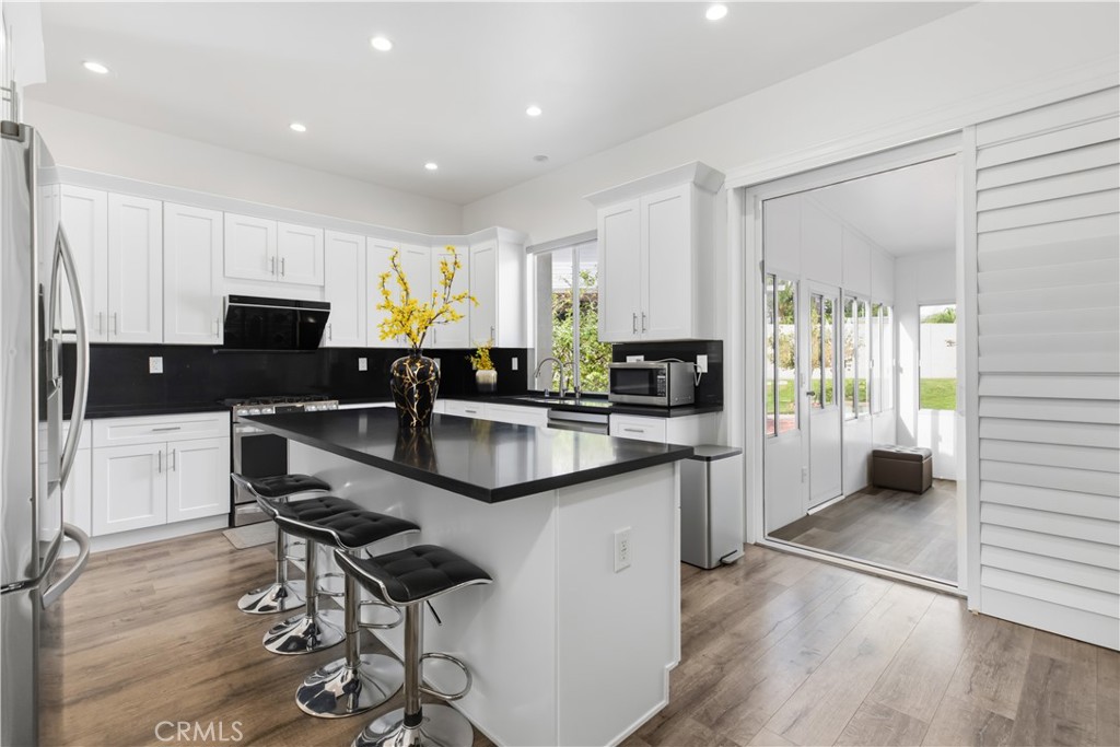 Kitchen with a large black-countertop island and sliding doors opening to a sunny enclosed sunroom.