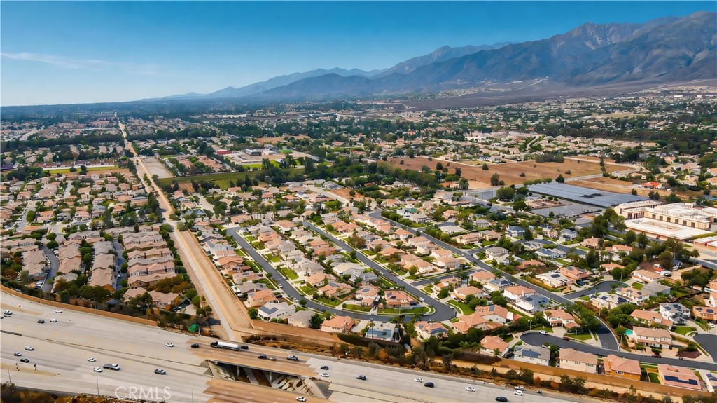 Aerial view of a Rancho Cucamonga neighborhood, with a freeway in front and mountains beyond.