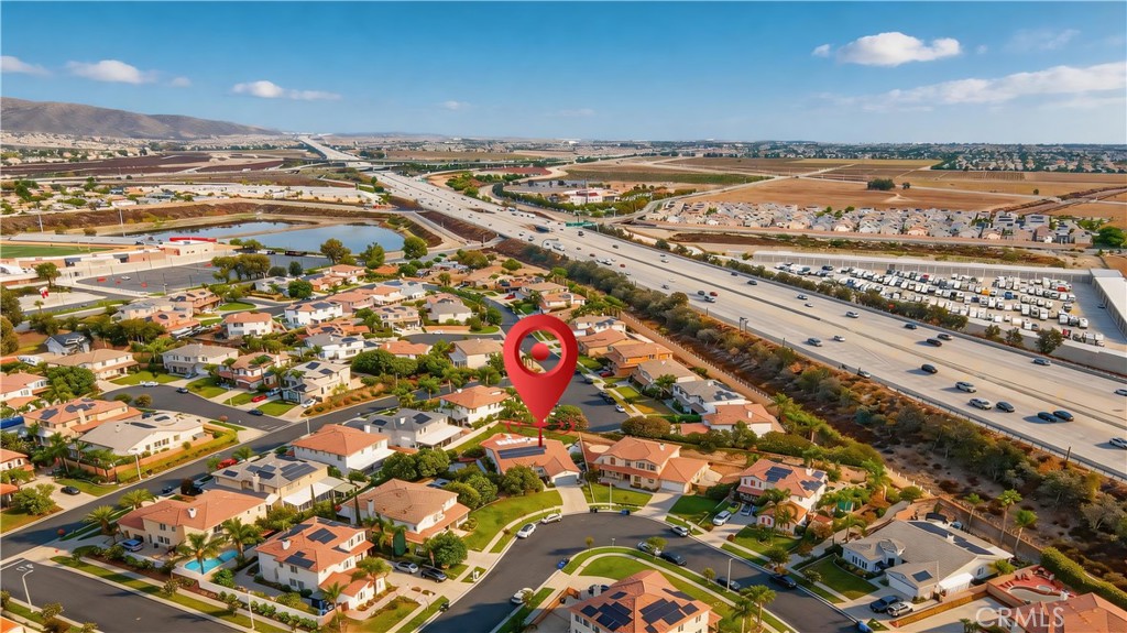 Aerial view of a residential neighborhood, with a red pin marking a home beside a freeway.