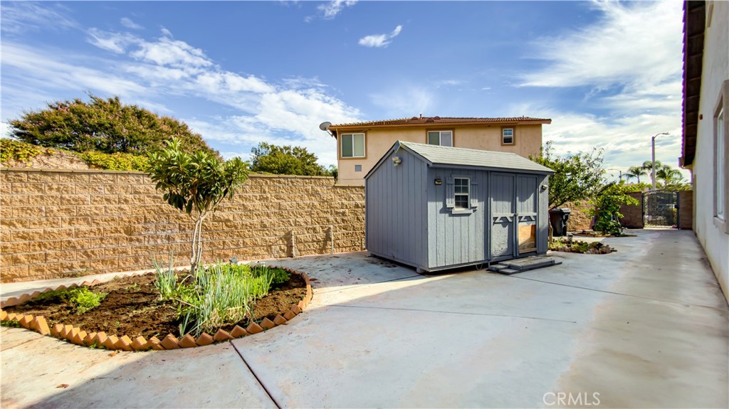 Backyard patio with a gray storage shed and raised garden bed.